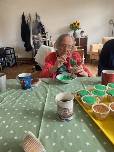 Resident putting green icing on a cupcake