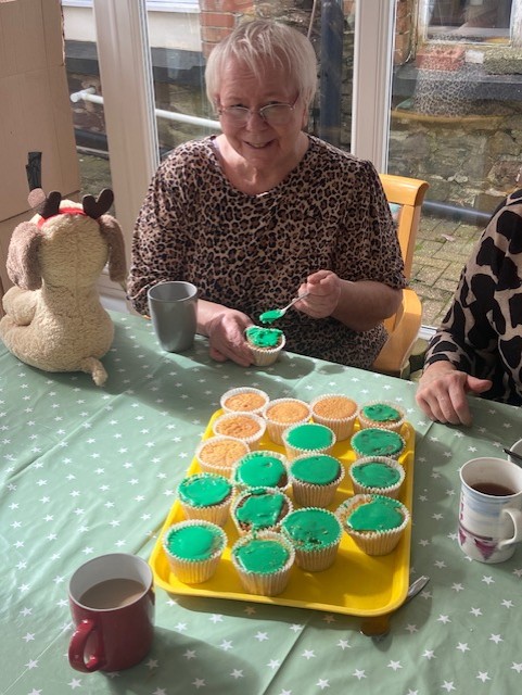 Resident putting green icing on a cupcake