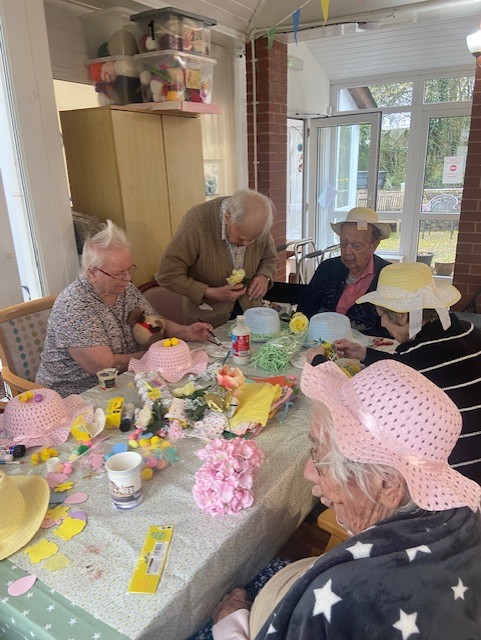 Residents around a table of Easter bonnets and decorations