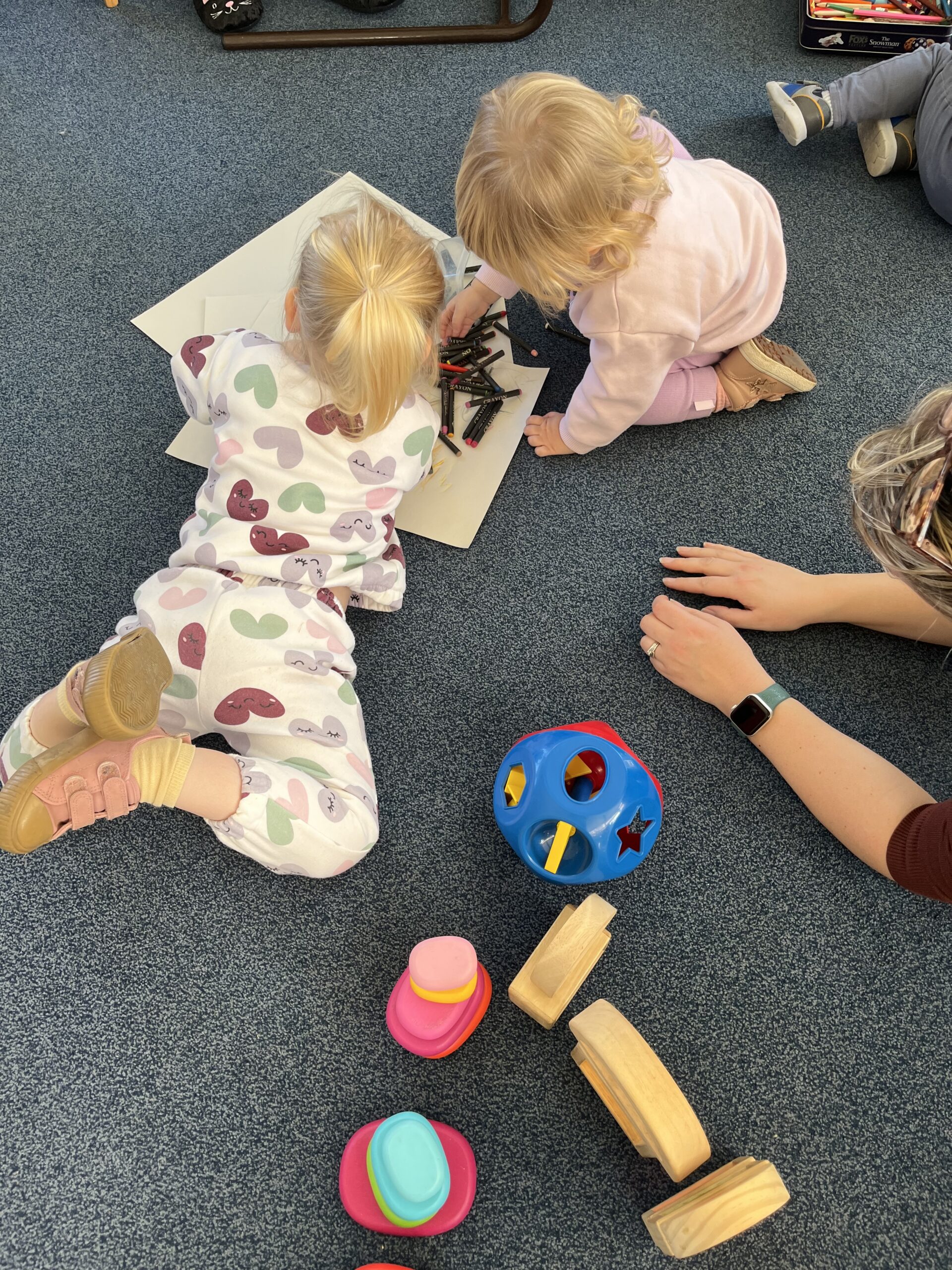 Toddlers playing on the floor with paper and crayons 1 scaled