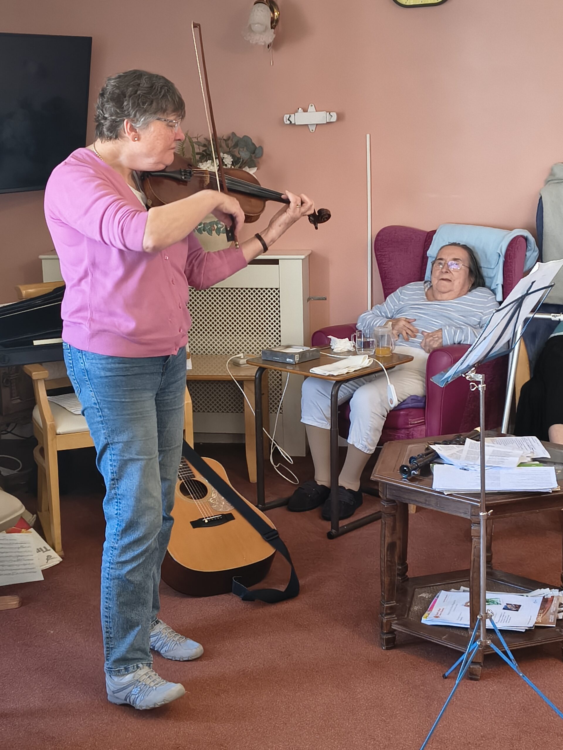 Alison playing the viola with a resident watching scaled