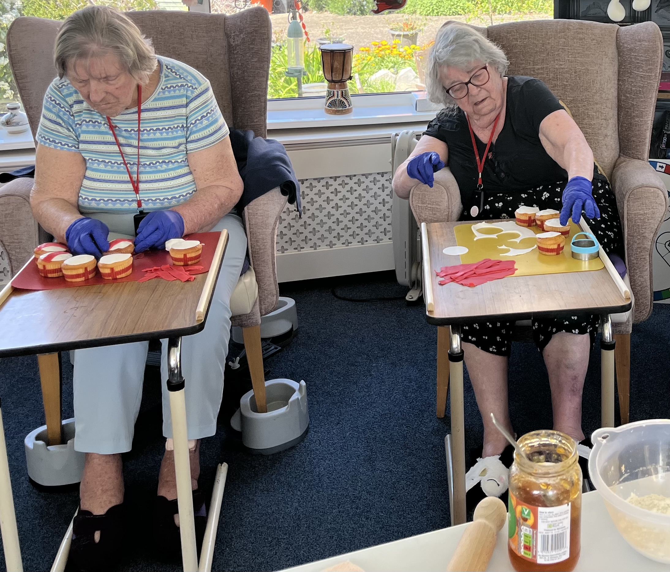 Barb and Maggie seated side by side decorating their cupcakes