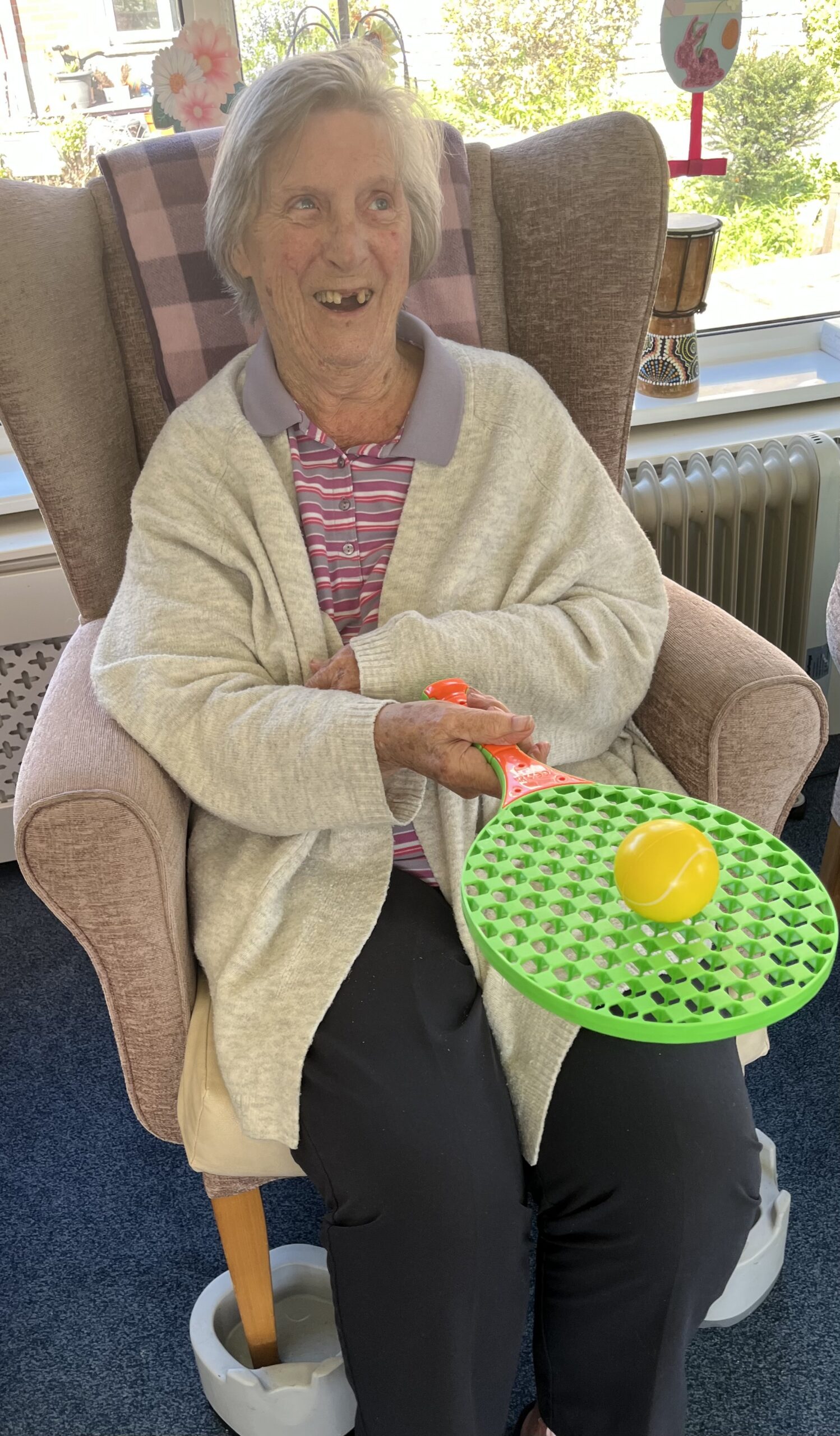 Barb balancing a tennis ball on a racket whilst seated scaled