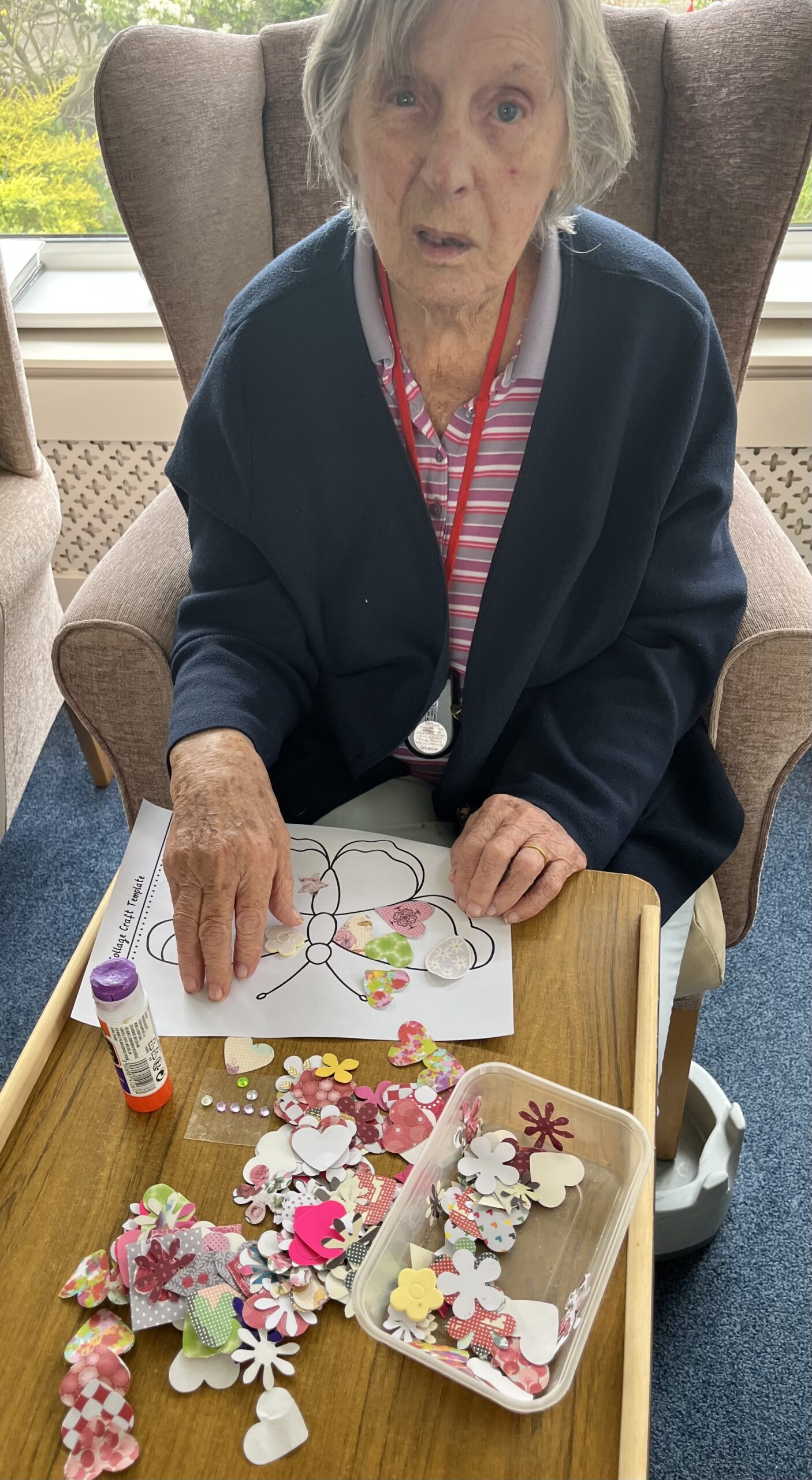 Barb gluing paper patterned shapes to her butterfly
