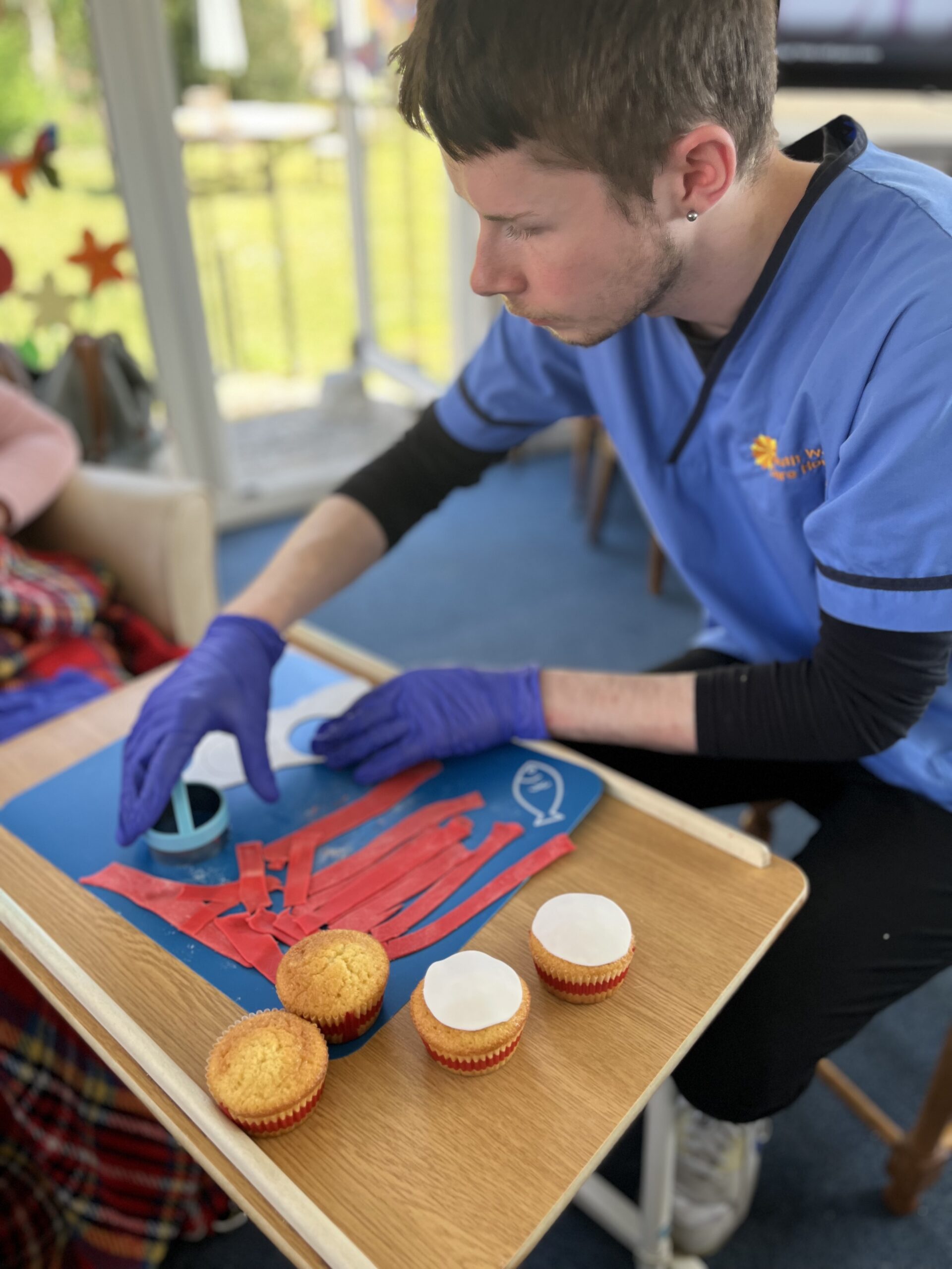 Carer Archie helping cut out white icing circles scaled
