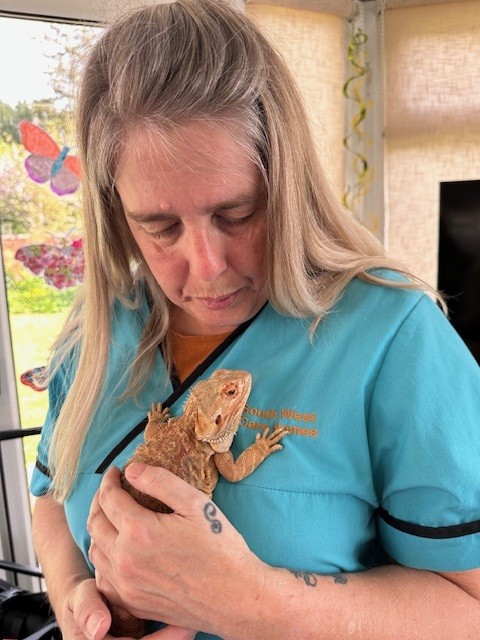 Carer Donna holding a Bearded Dragon to her chest