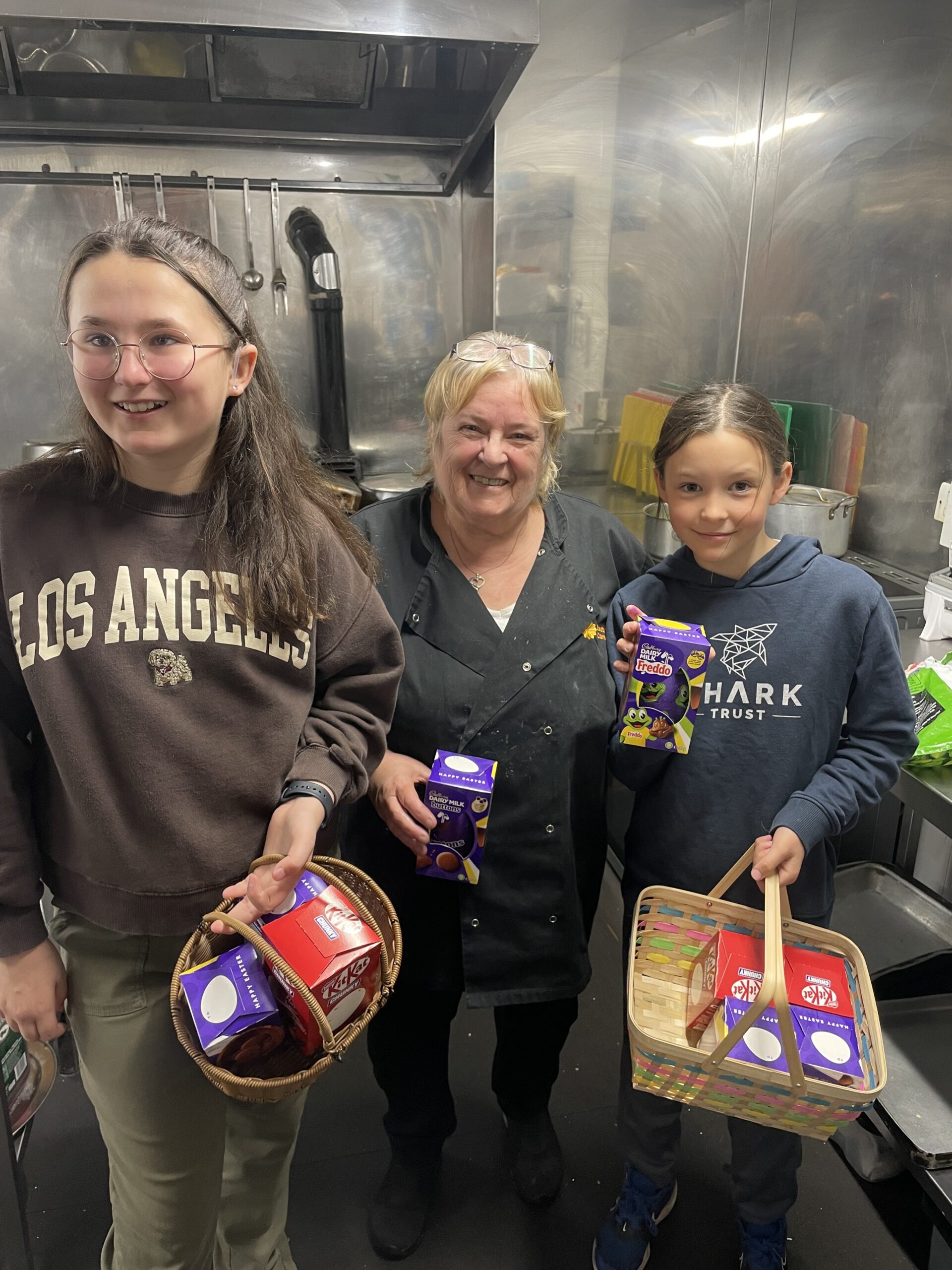 Carer with helpers holding baskets of chocolate Easter eggs scaled