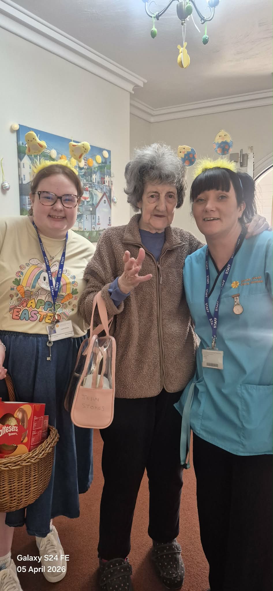 Female resident and two carers with fluffy chick hairbands and a basket of chocolate eggs