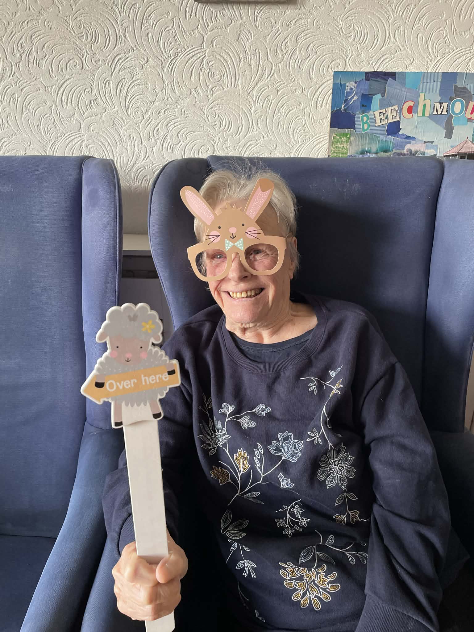 Female resident holding Easter sign and wearing bunny glasses