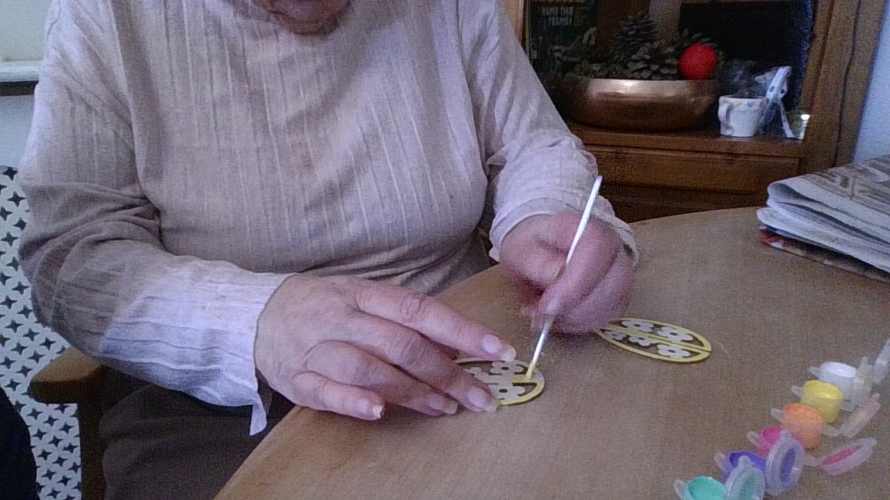 Female resident painting flowers on a paper egg
