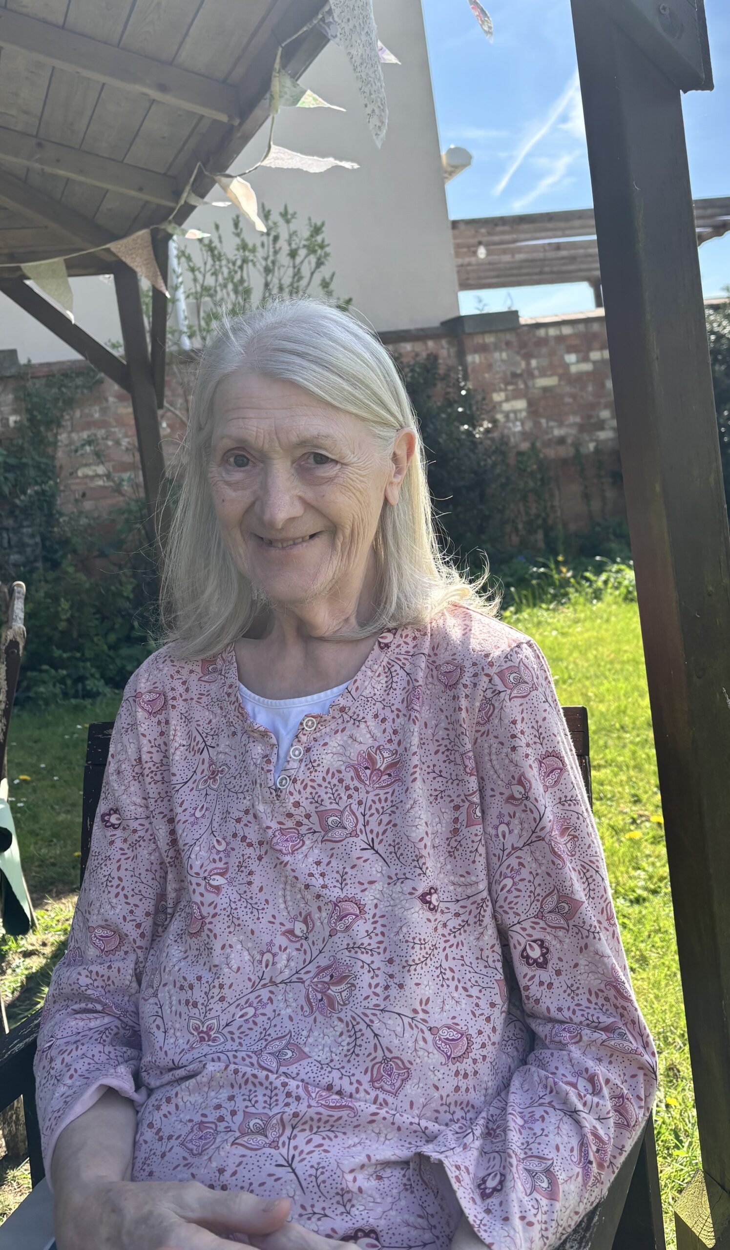 Female resident sat outside in the garden under the gazebo scaled