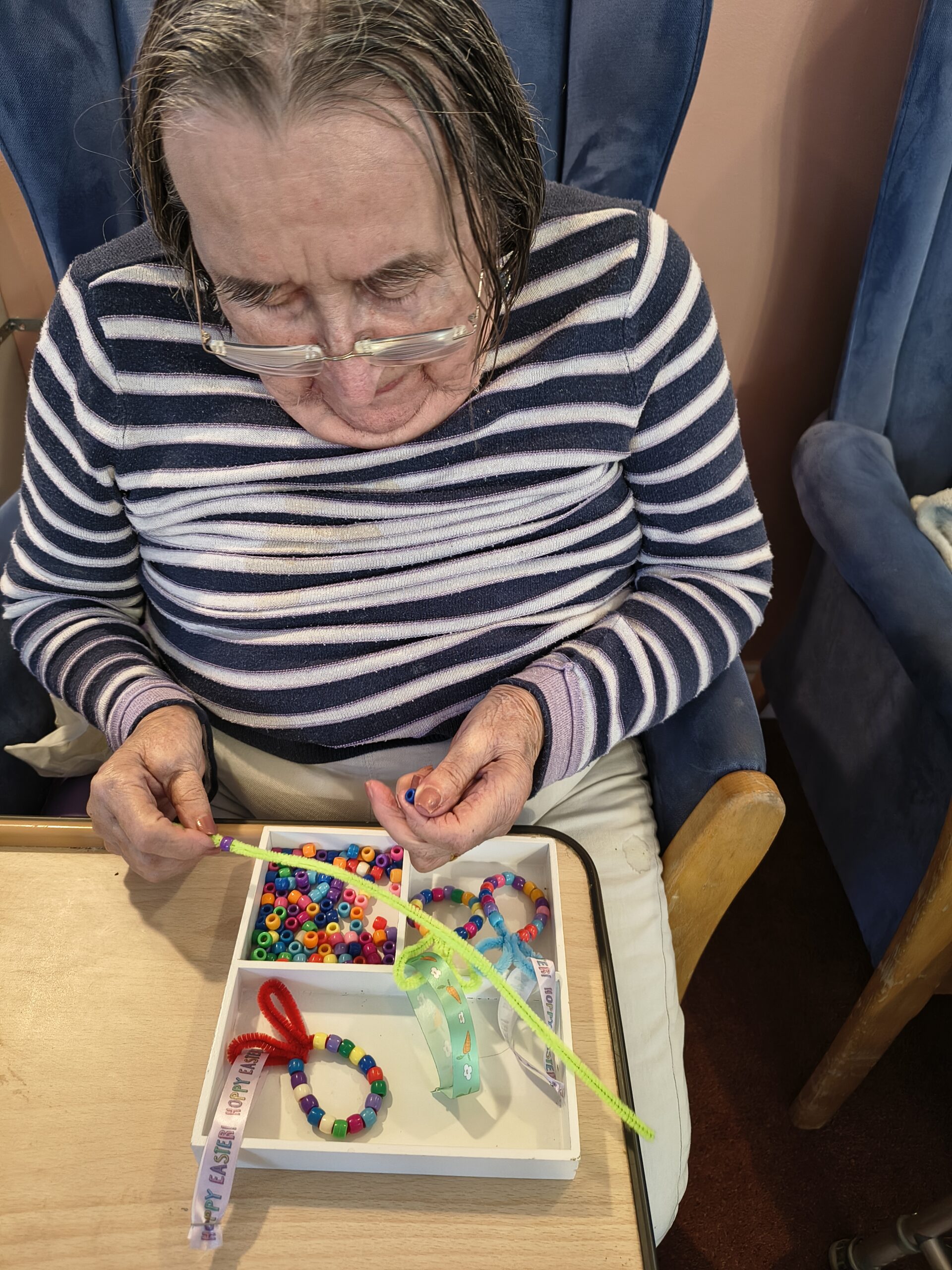 Female resident threading beads onto a pipe cleaner