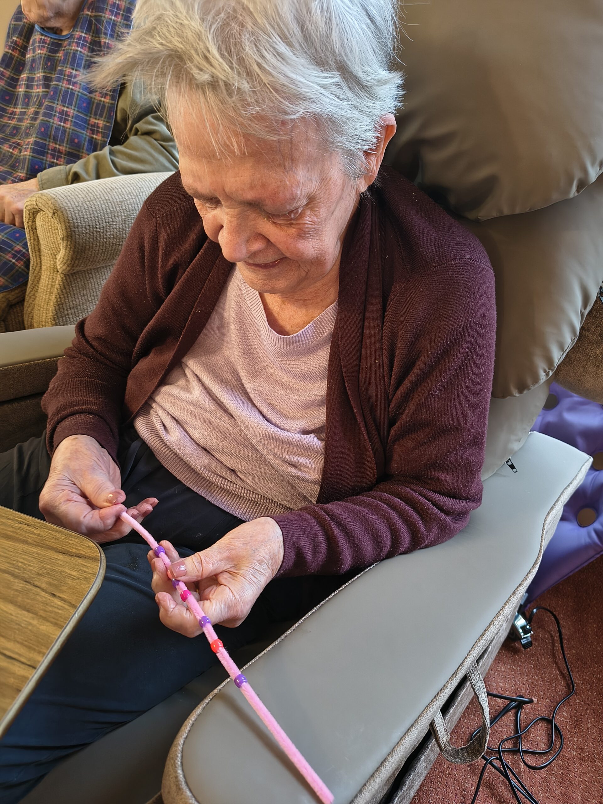 Female resident threading beads onto a pipe cleaner