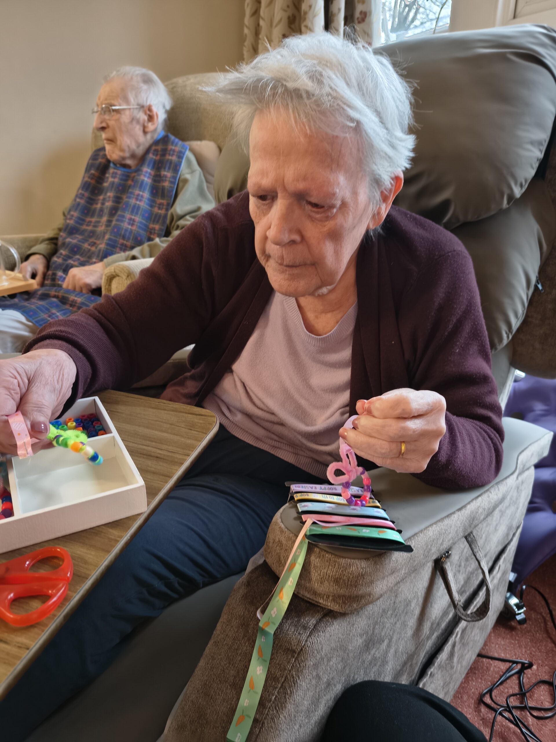 Female resident threading beads onto a pipe cleaner