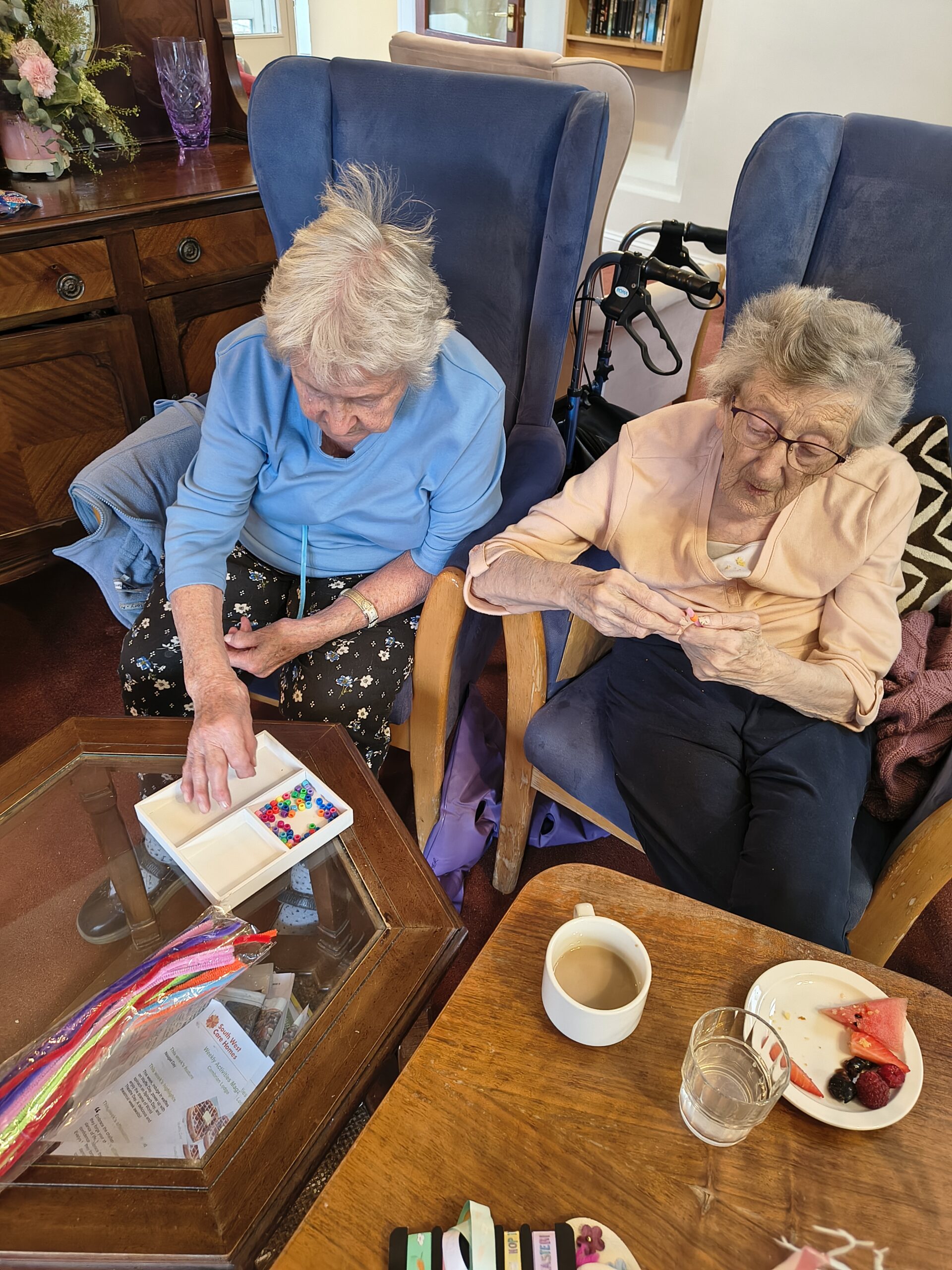 Female residents threading beads onto a pipe cleaner