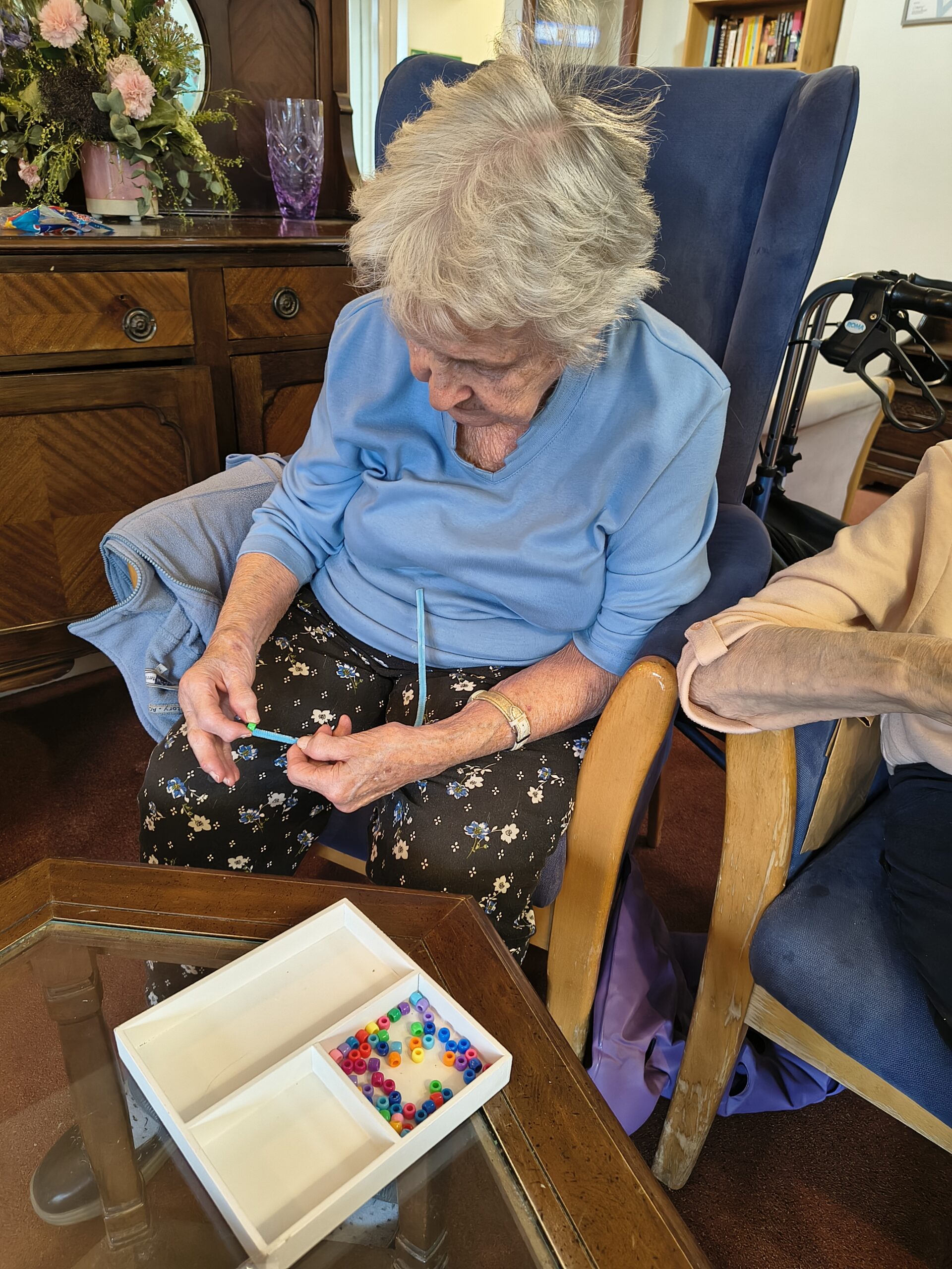 Female resident threading beads onto a pipe cleaner