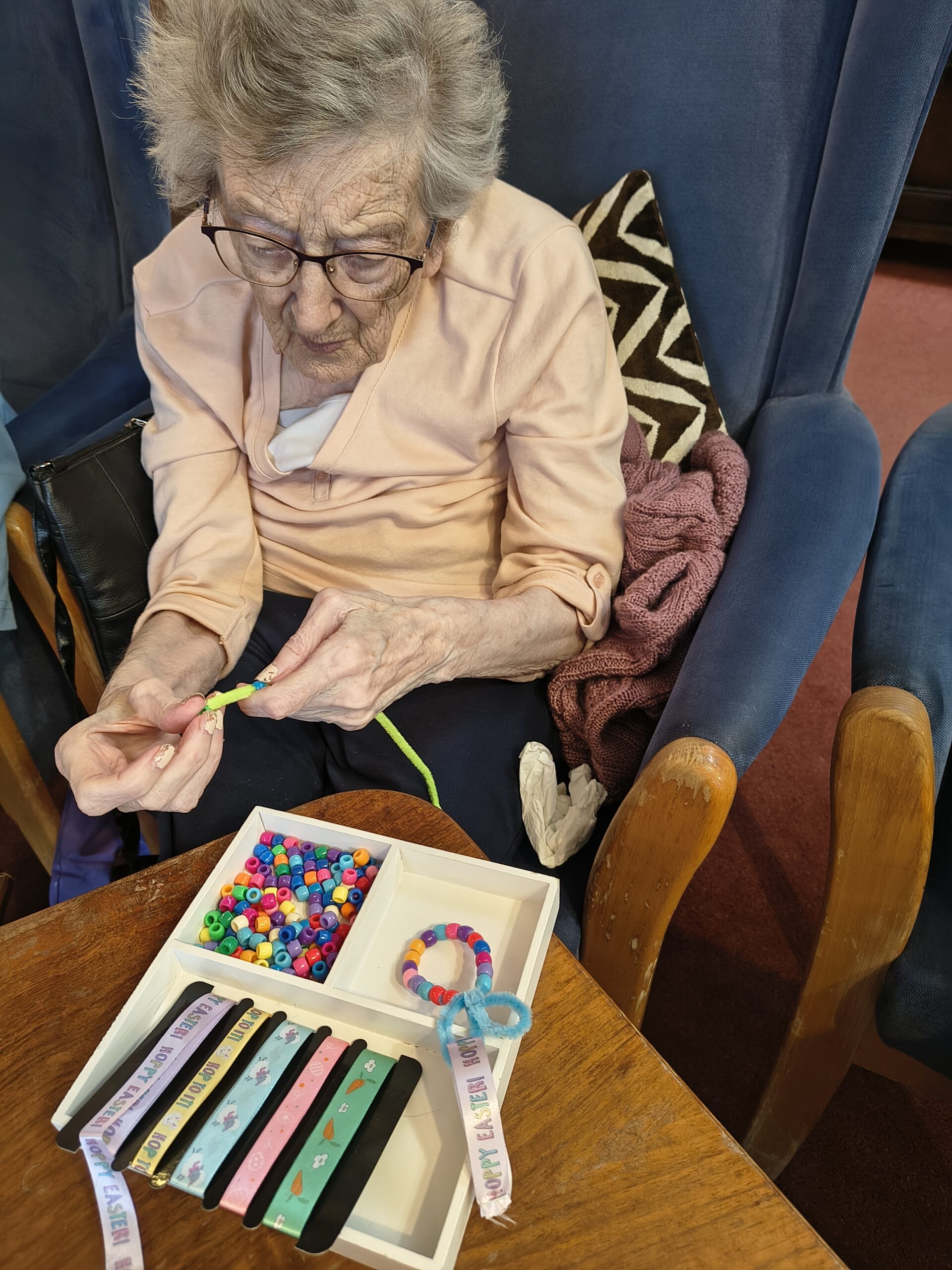 Female resident threading beads onto a pipe cleaner