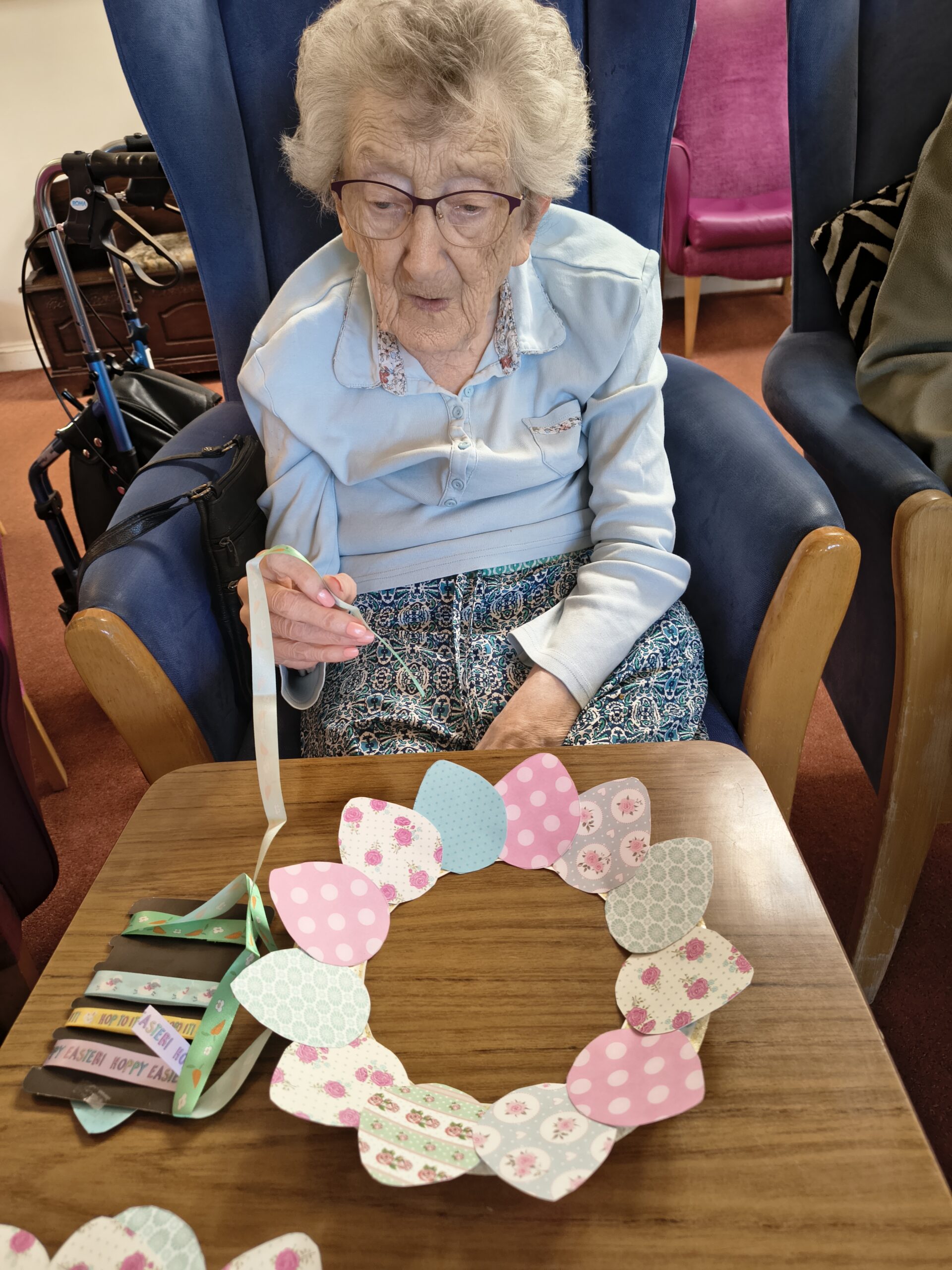 Female resident threading the Easter ribbon onto the wreath scaled