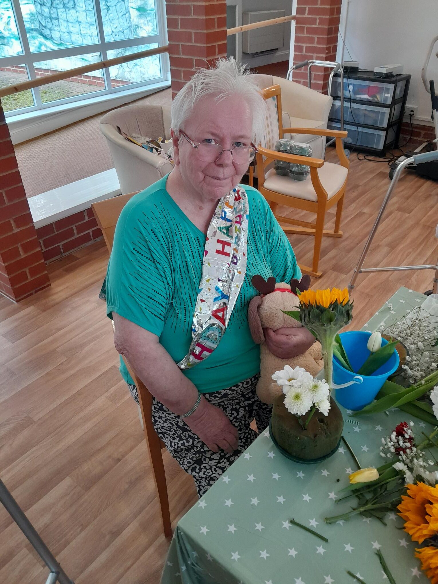 Female resident wearing a Happy Birthday sash whilst flower arranging rotated