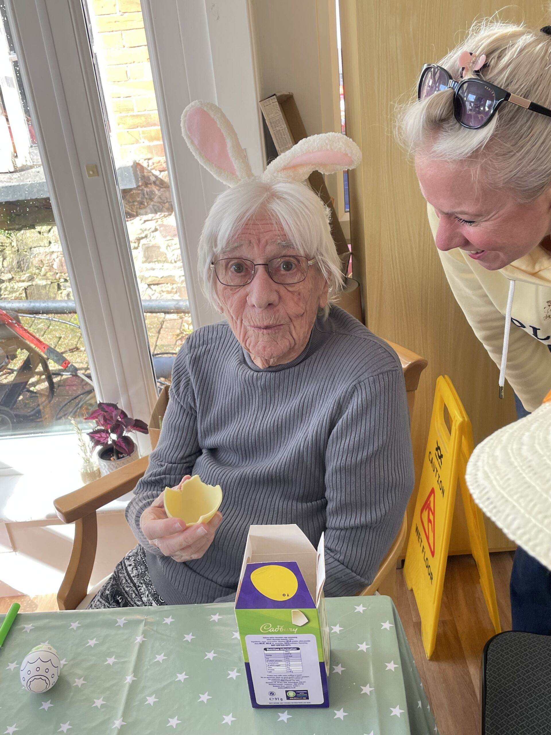 Female resident wearing white bunny ears hairband eating a white chocolate Easter egg scaled