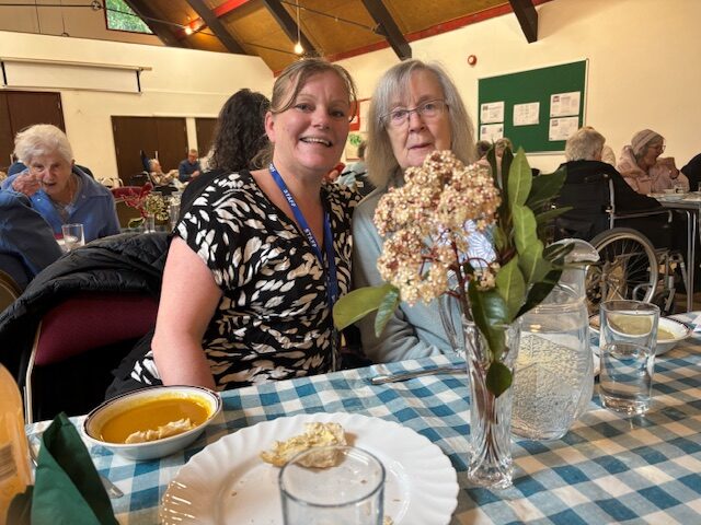 Female resident with carer enjoying soup
