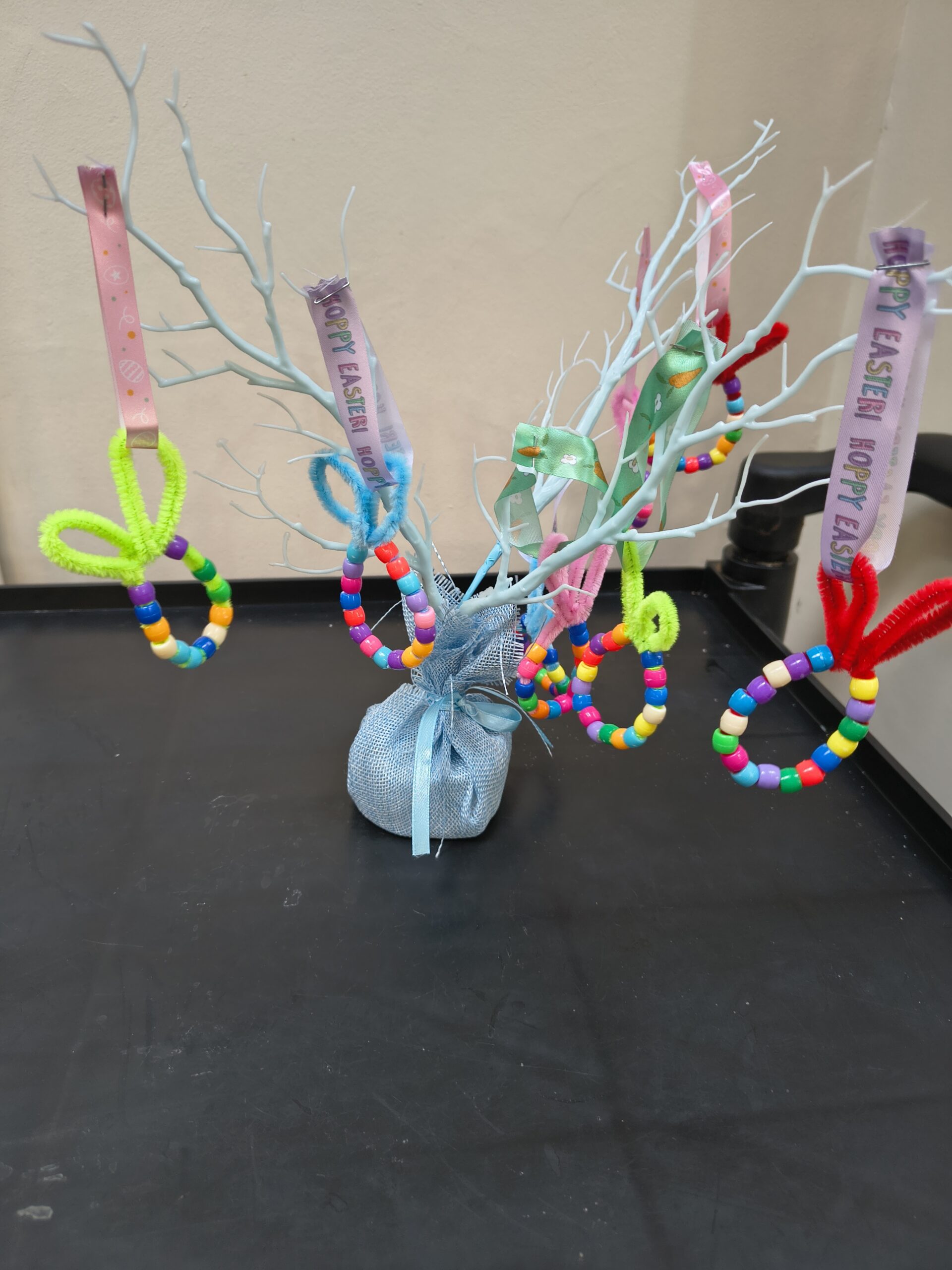 Finished beaded Easter eggs on display, hanging on a small white twig tree