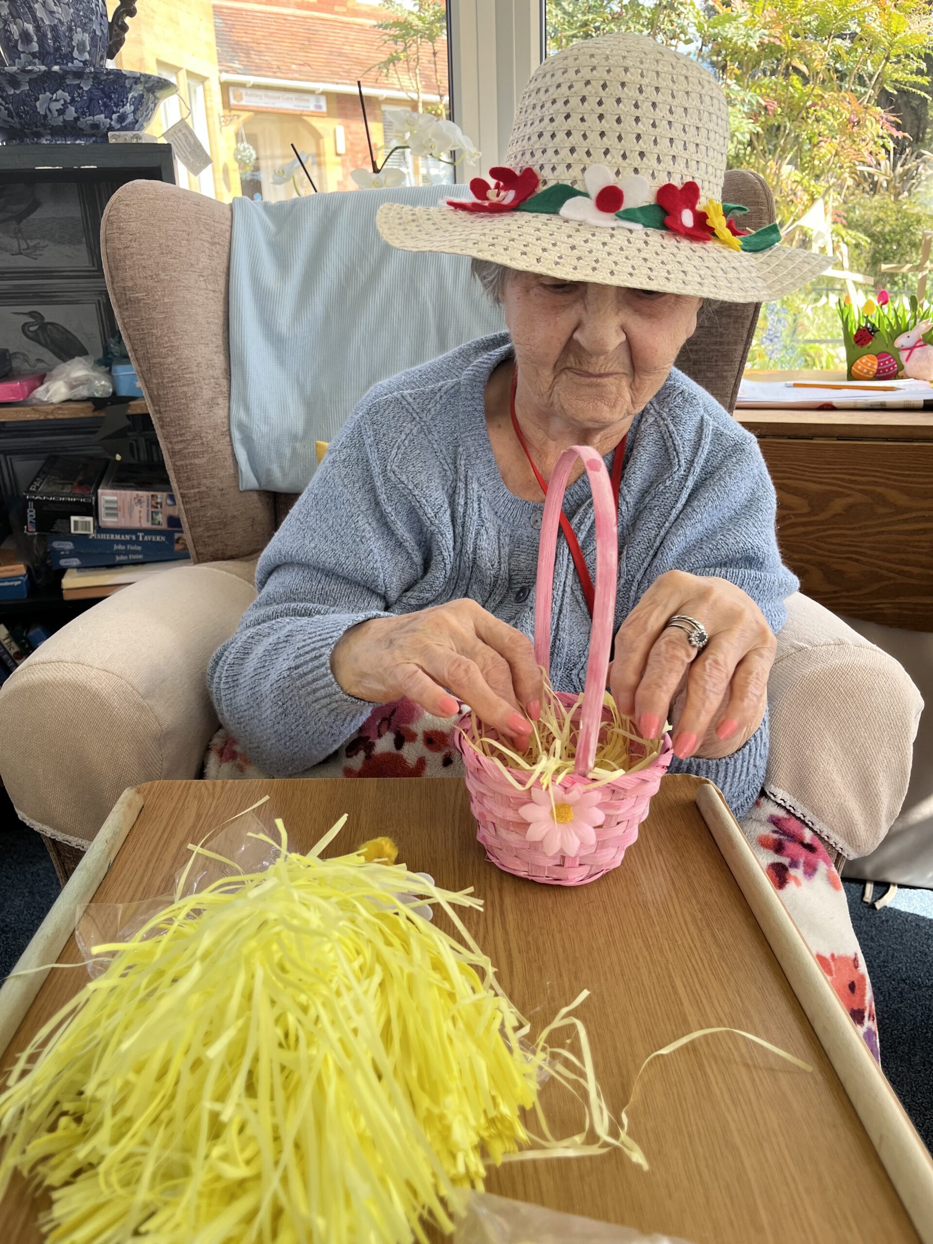 Herta filling her pale pink Easter basket with yellow paper straw scaled