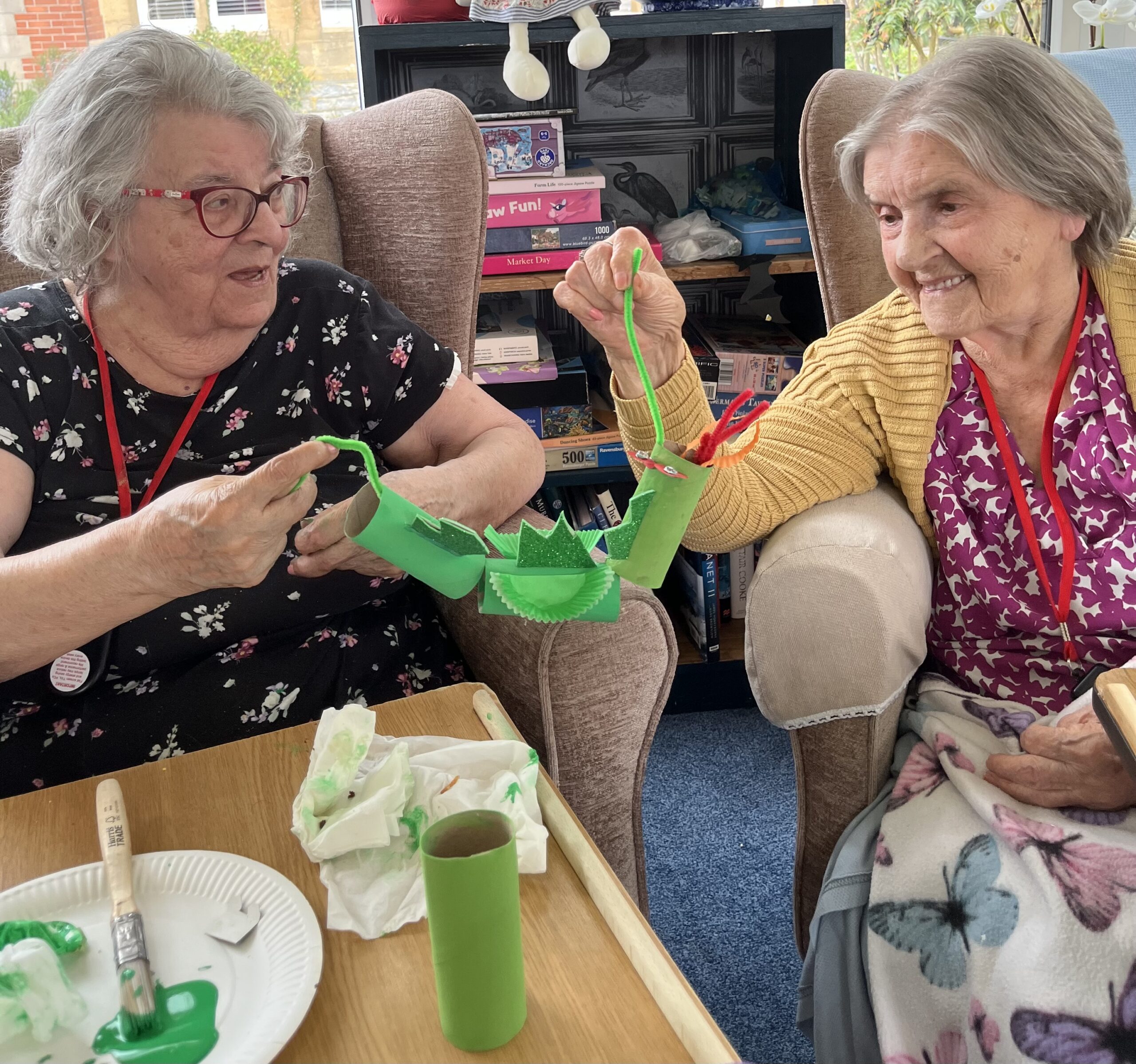Maggie and Herta talking about a dragon holding each end of a pipe cleaner