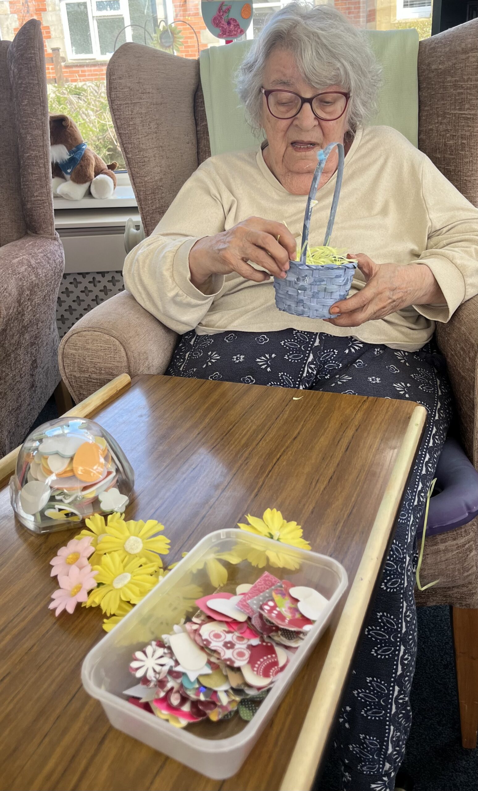 Maggie decorating her Easter basket with yellow paper flowers scaled