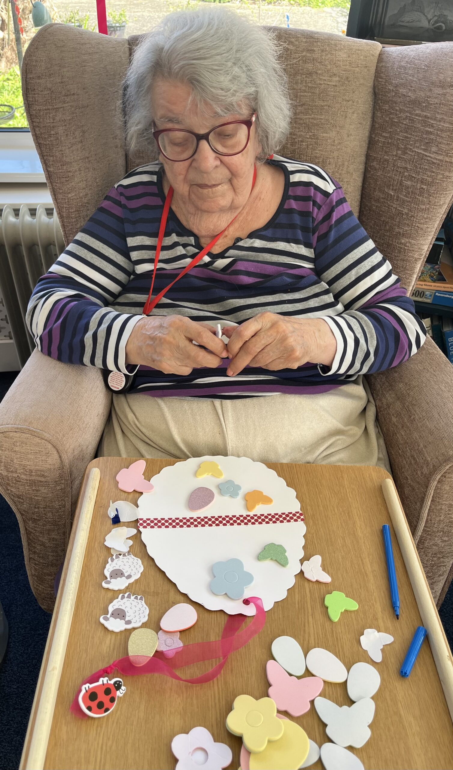 Maggie sticking butterfly stickers on to her egg shaped paper scaled