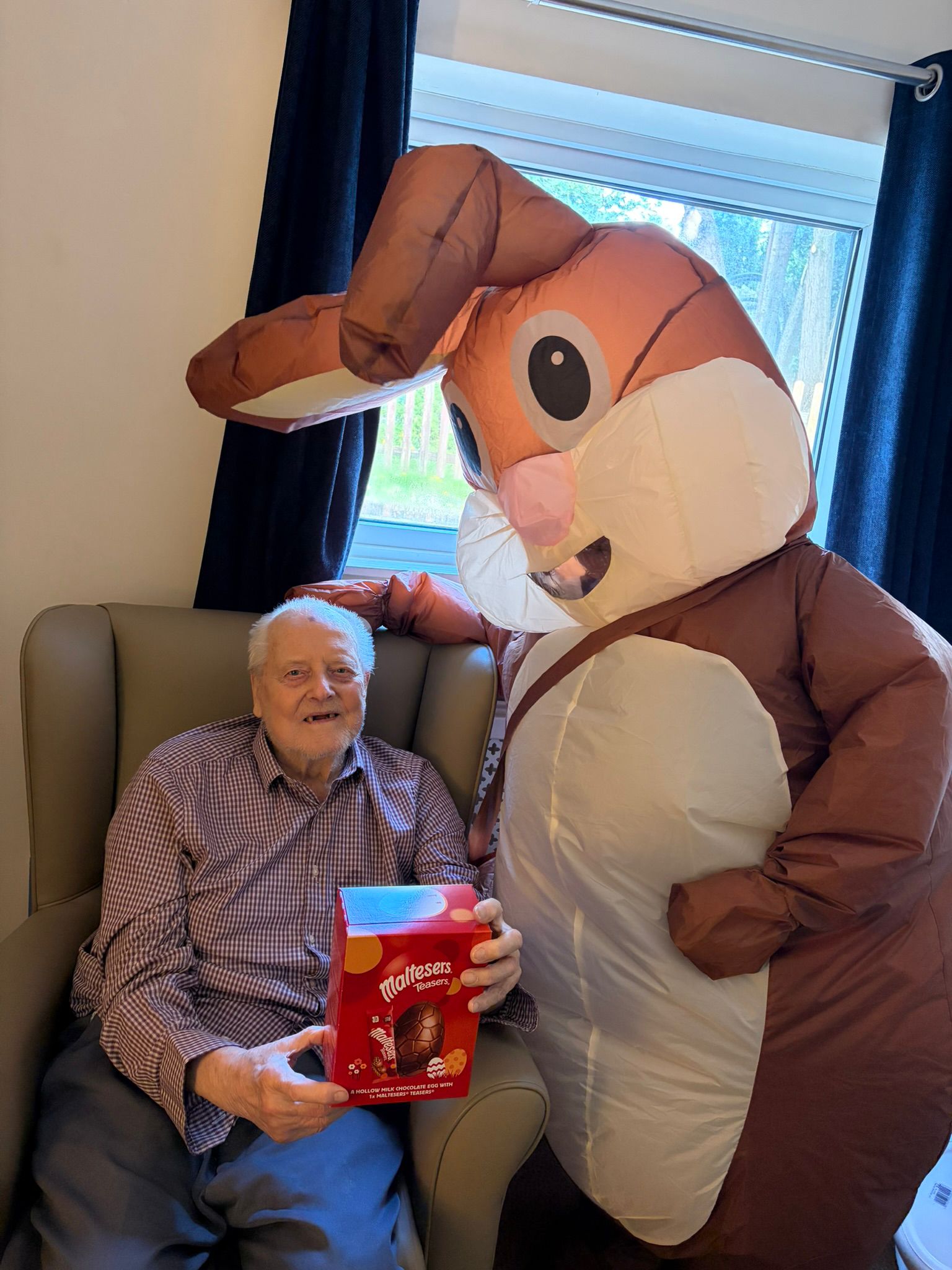 Male resident pictured with the Easter bunny receiving an egg