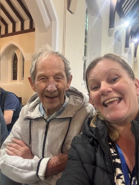 Male resident posing for a selfie with a carer in the church