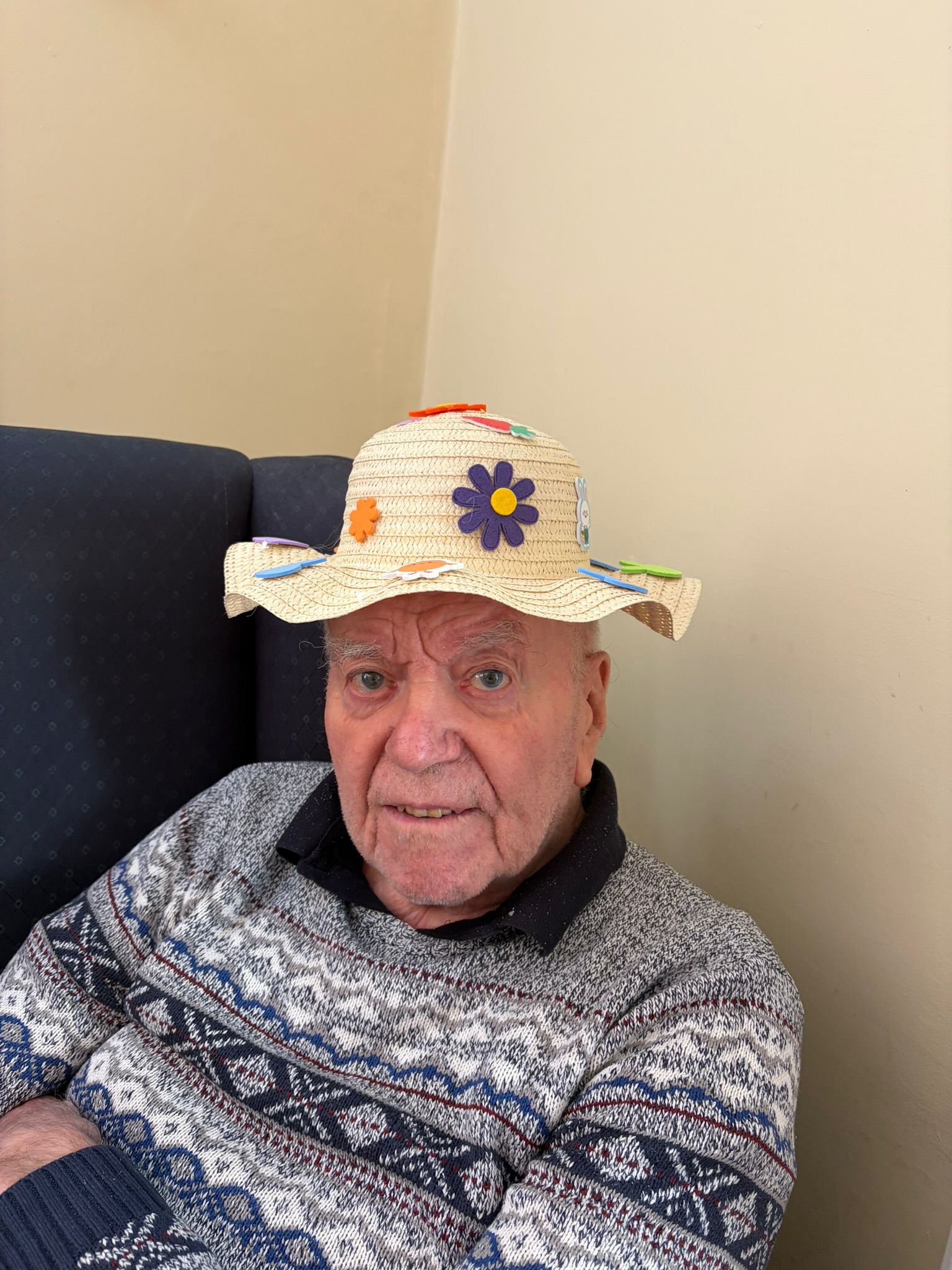 Male resident seated inside with Easter bonnet