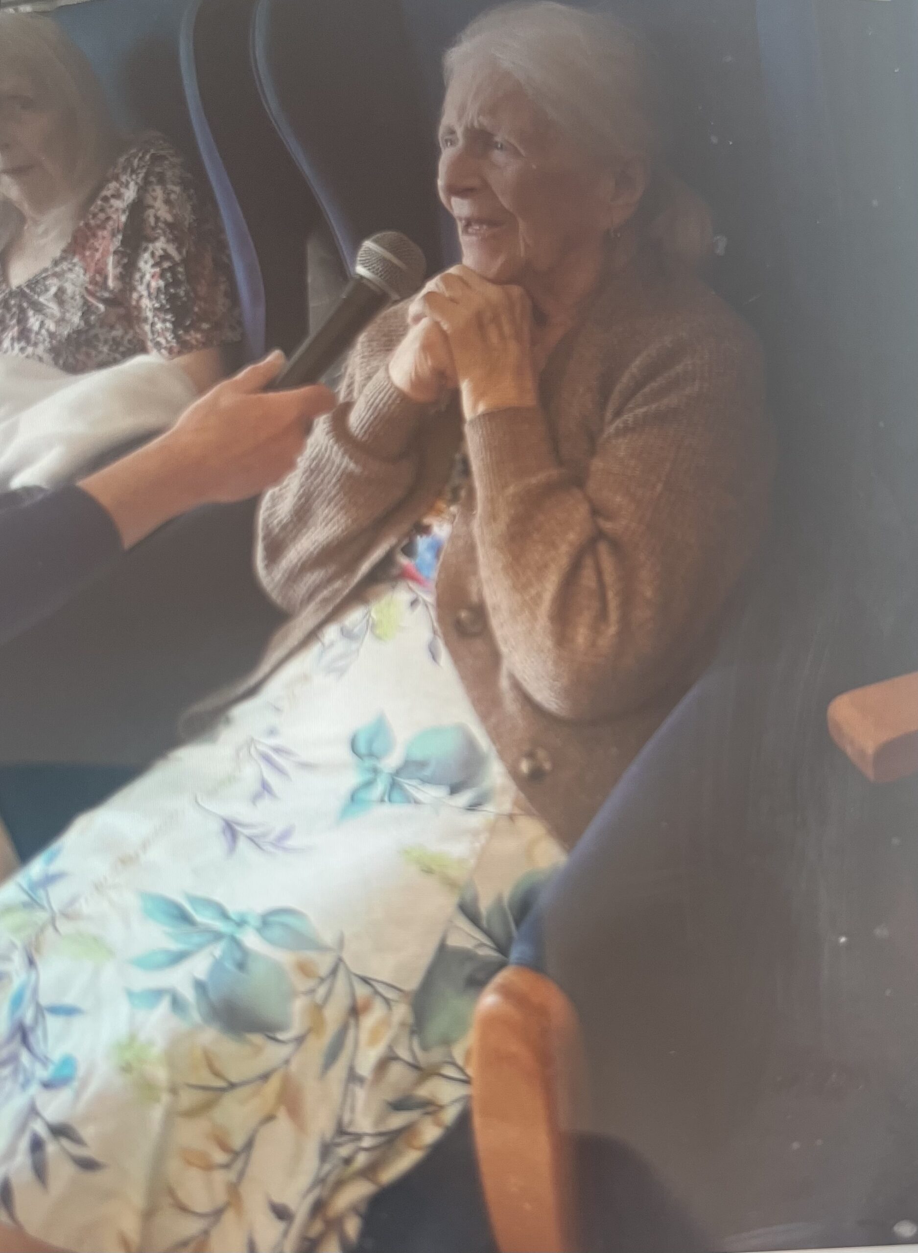 Mary enjoying the spotlight singing into a microphone scaled