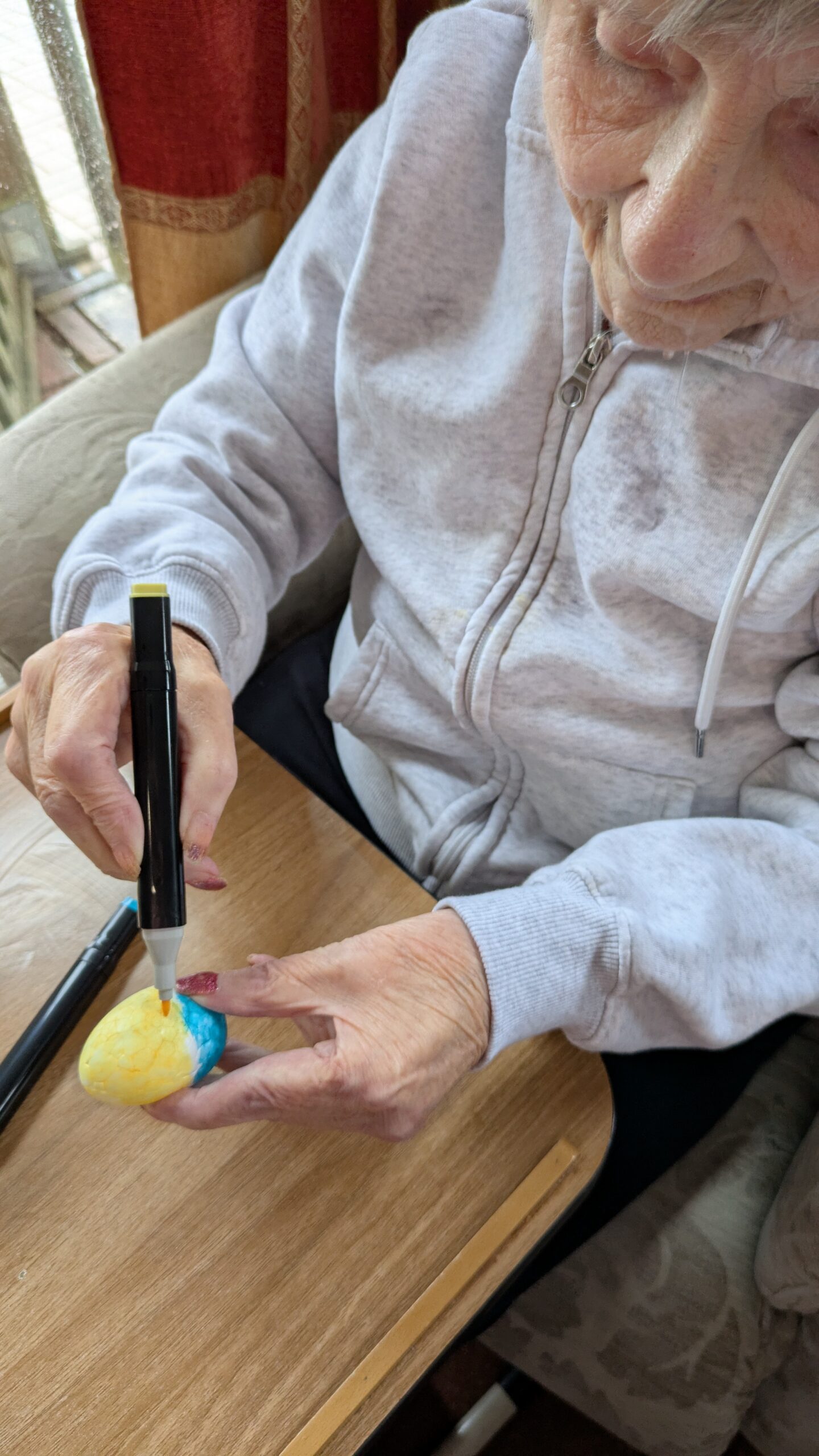 Mo decorating her foam Easter egg with yellow and blue felt-tip pen