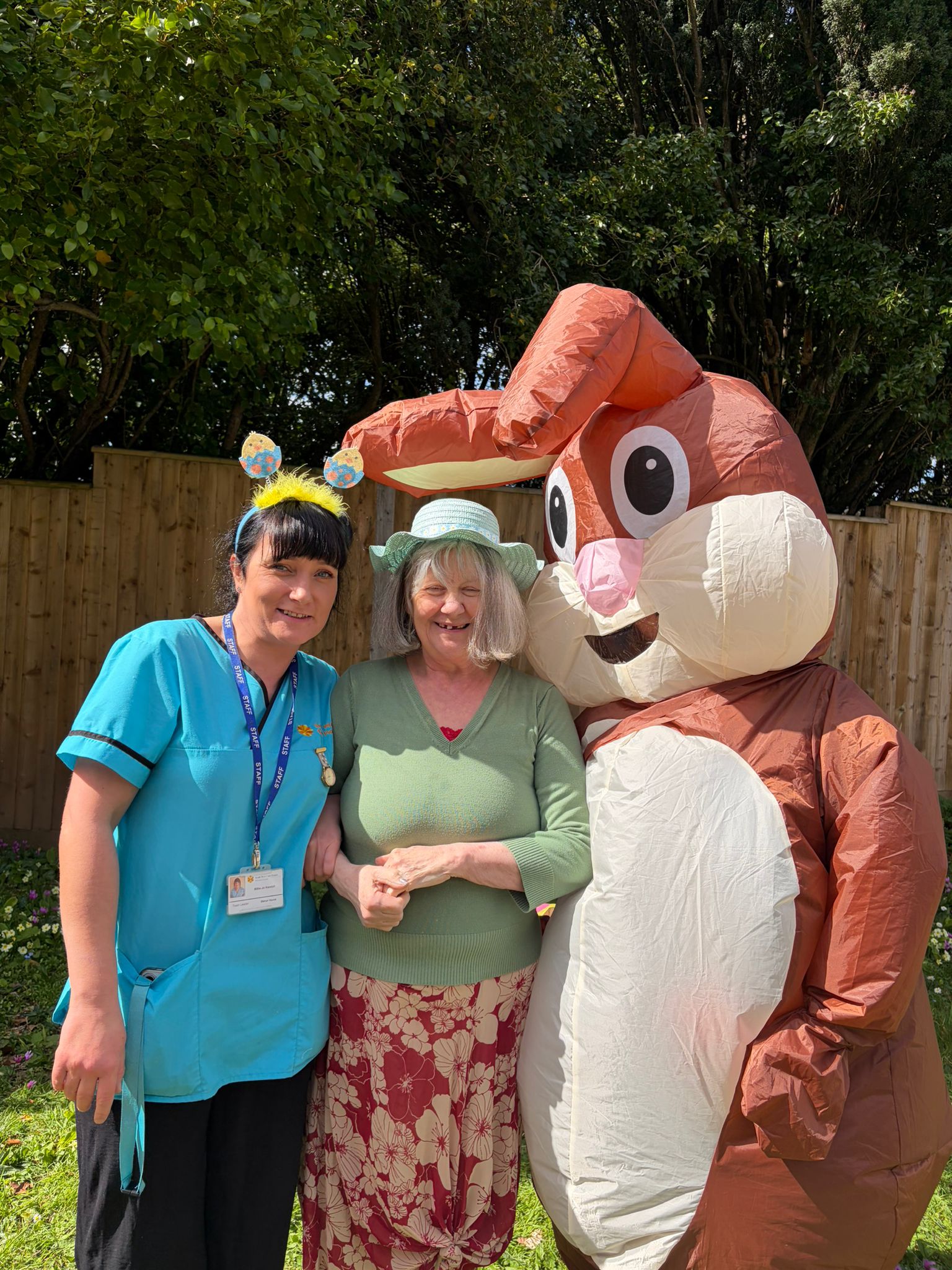 Resident and carer outside in the garden posing for a photo with the Easter bunny