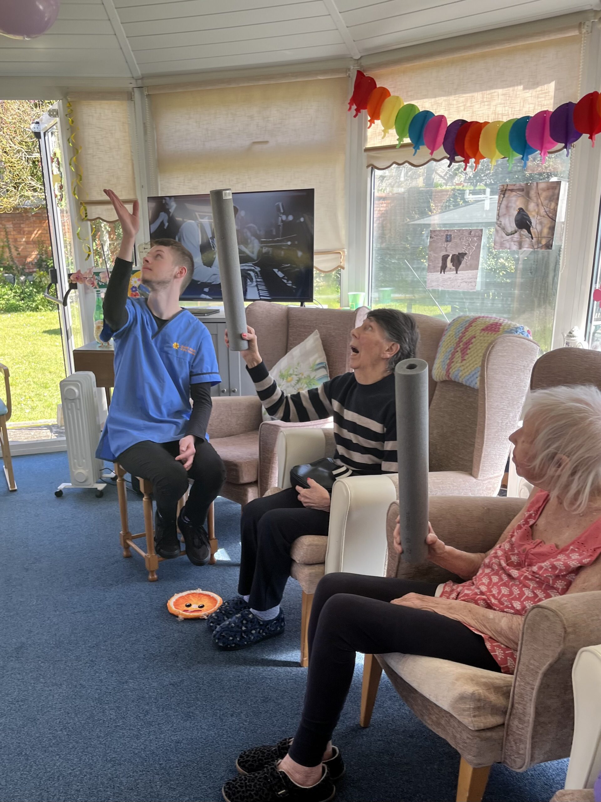 Residents and a carer keeping a balloon in the air with foam insulation pipe scaled