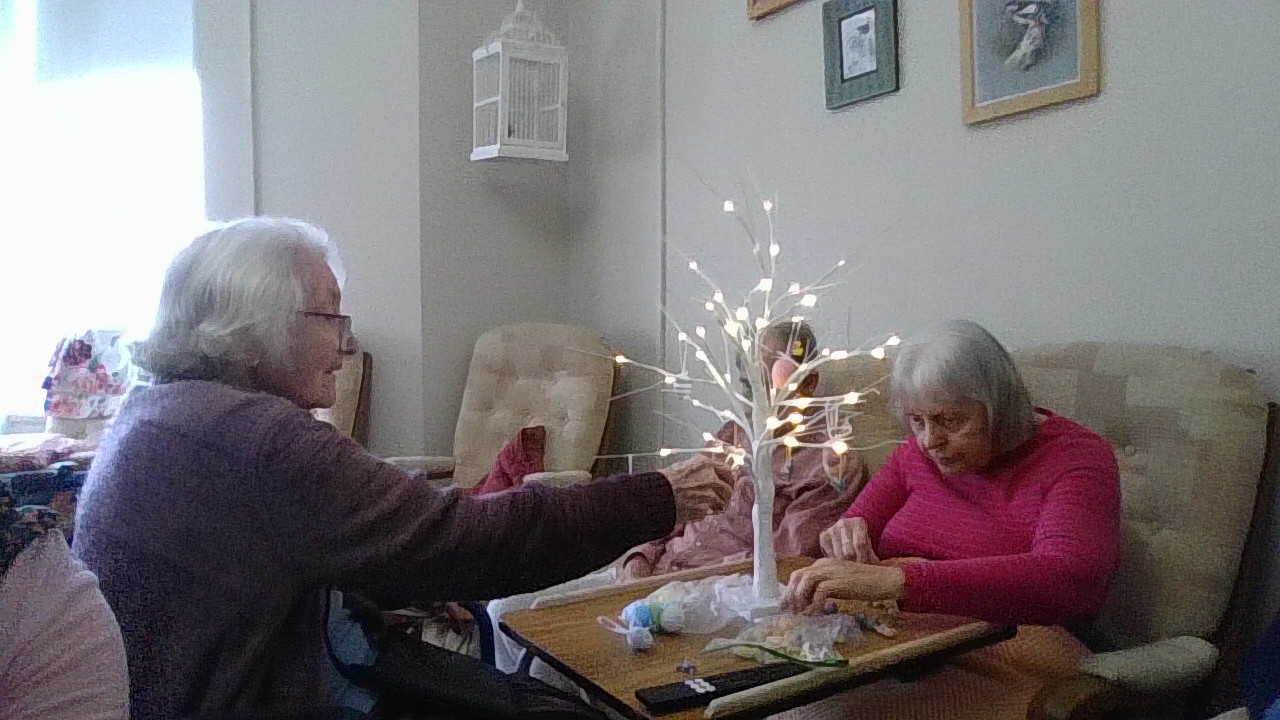 Residents decorating a decorative white tree stand with Easter decorations