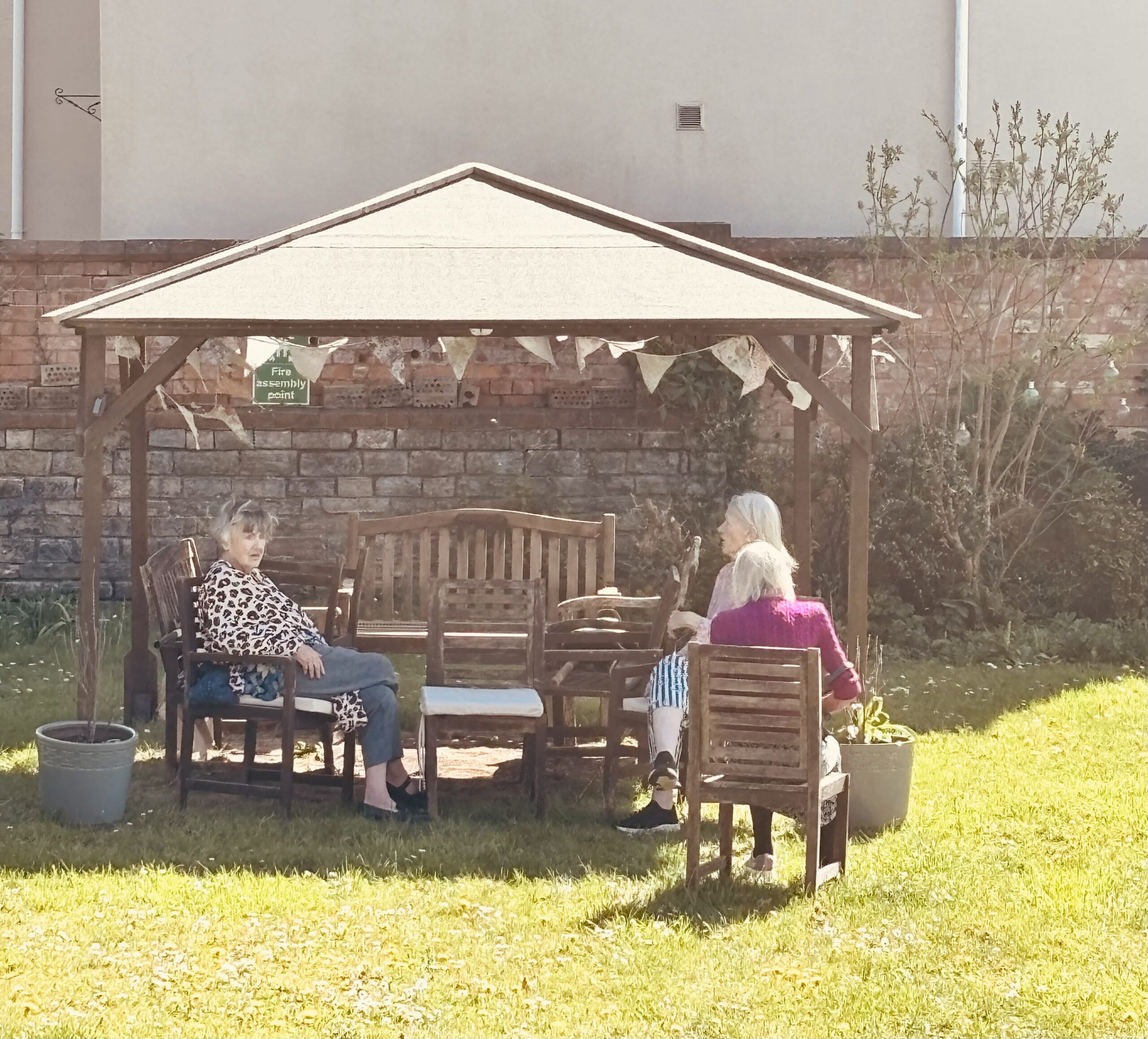 Residents sat outside under wooden gazebo in the garden scaled