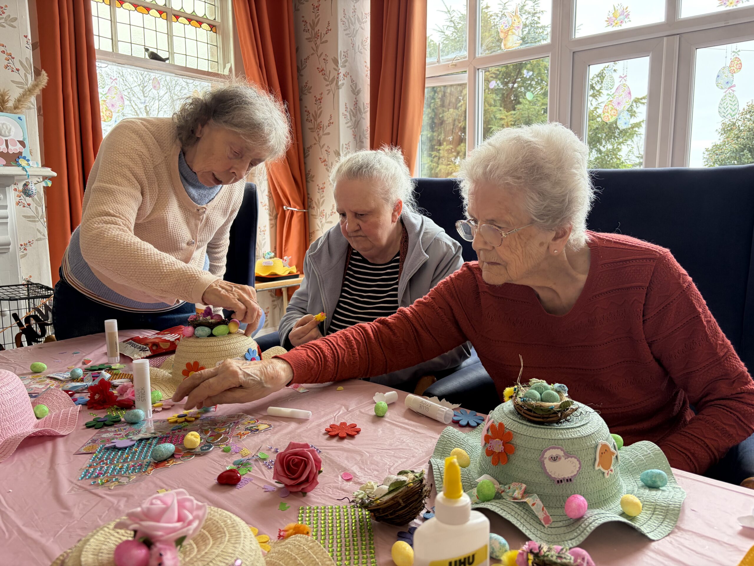 Residents seated around a table decorating Easter bonnets