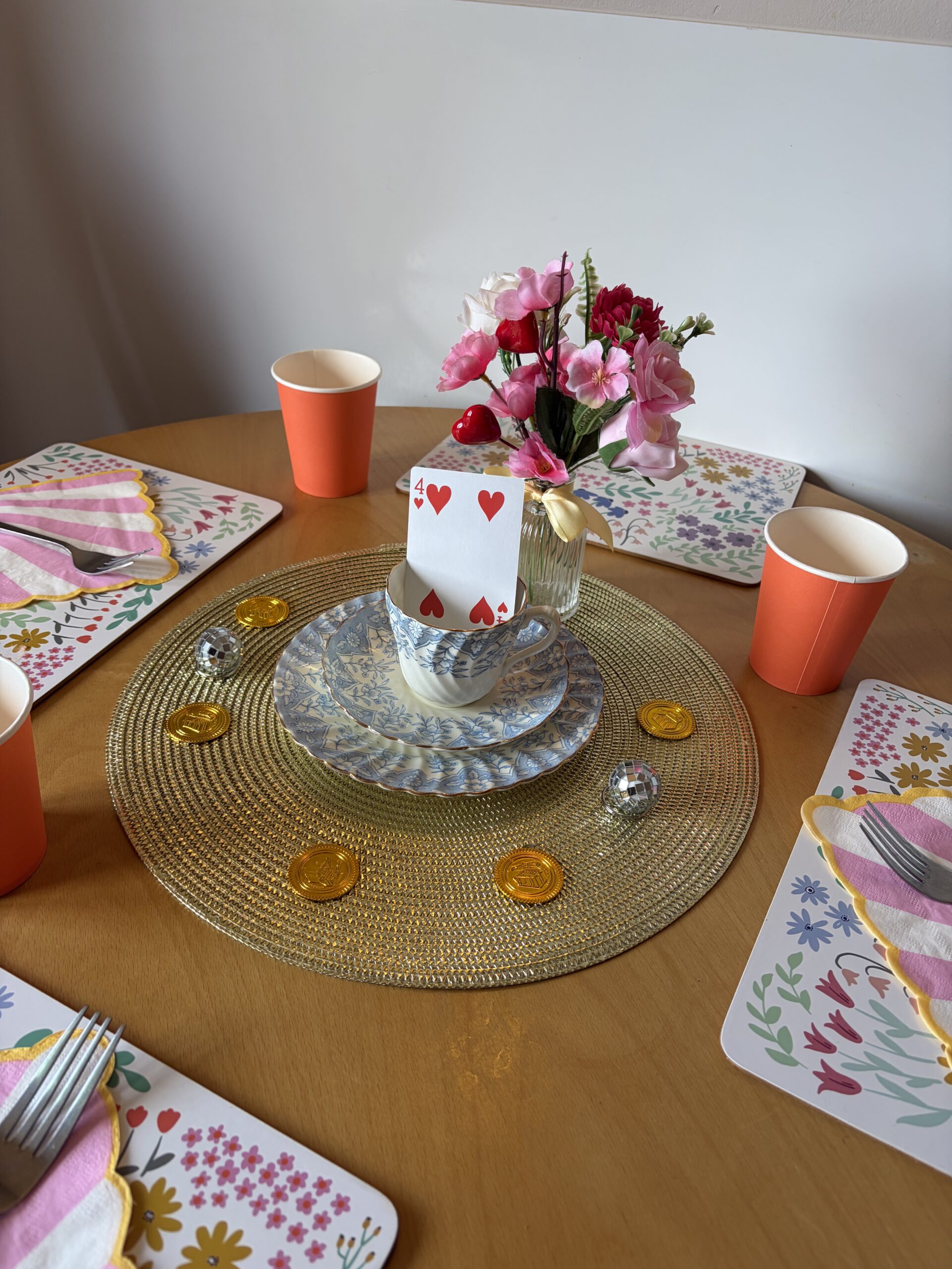 Table decoration of teacup and saucers with a playing card, gold coins and mini disco balls