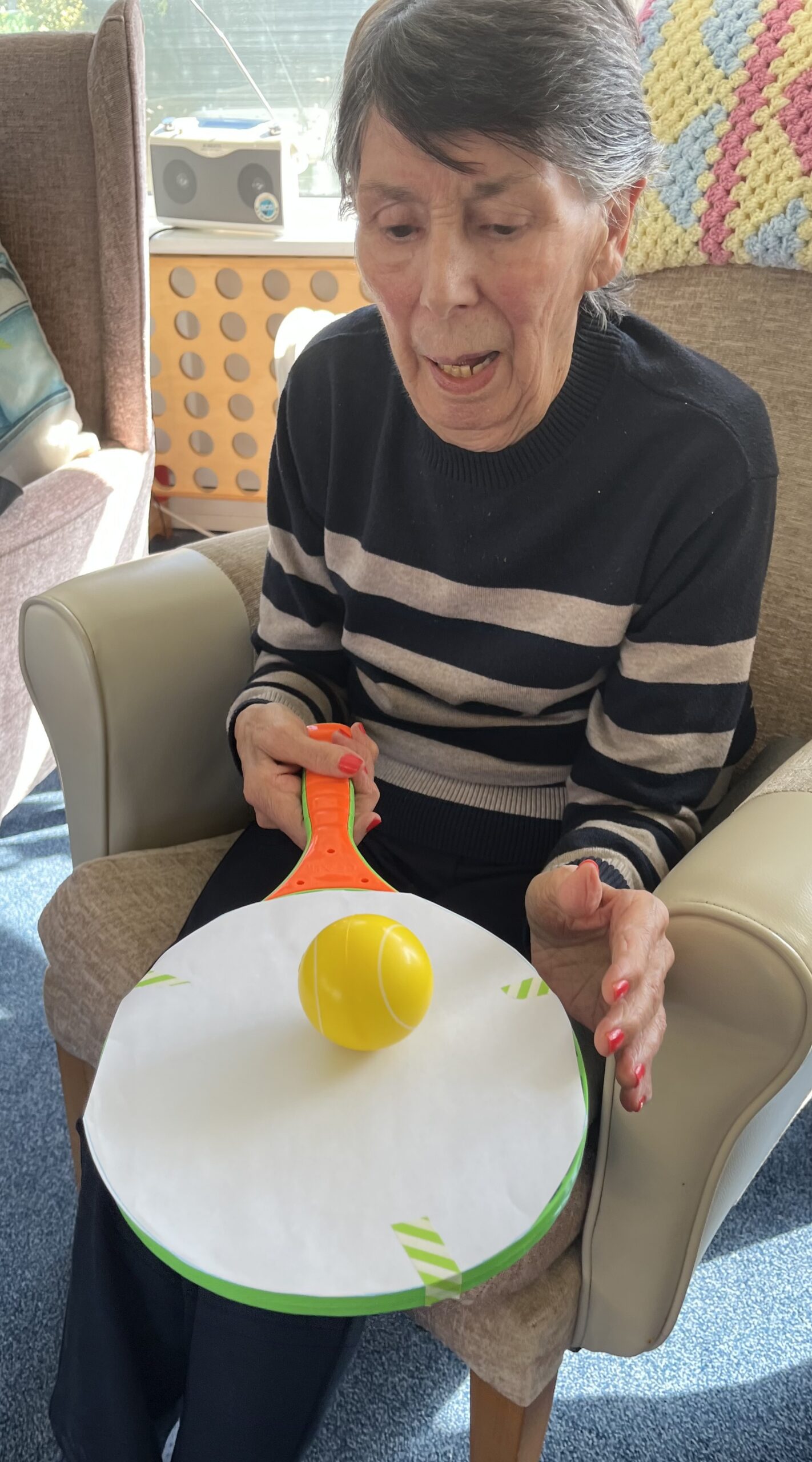 Violet balancing a tennis ball on a racket whilst seated scaled
