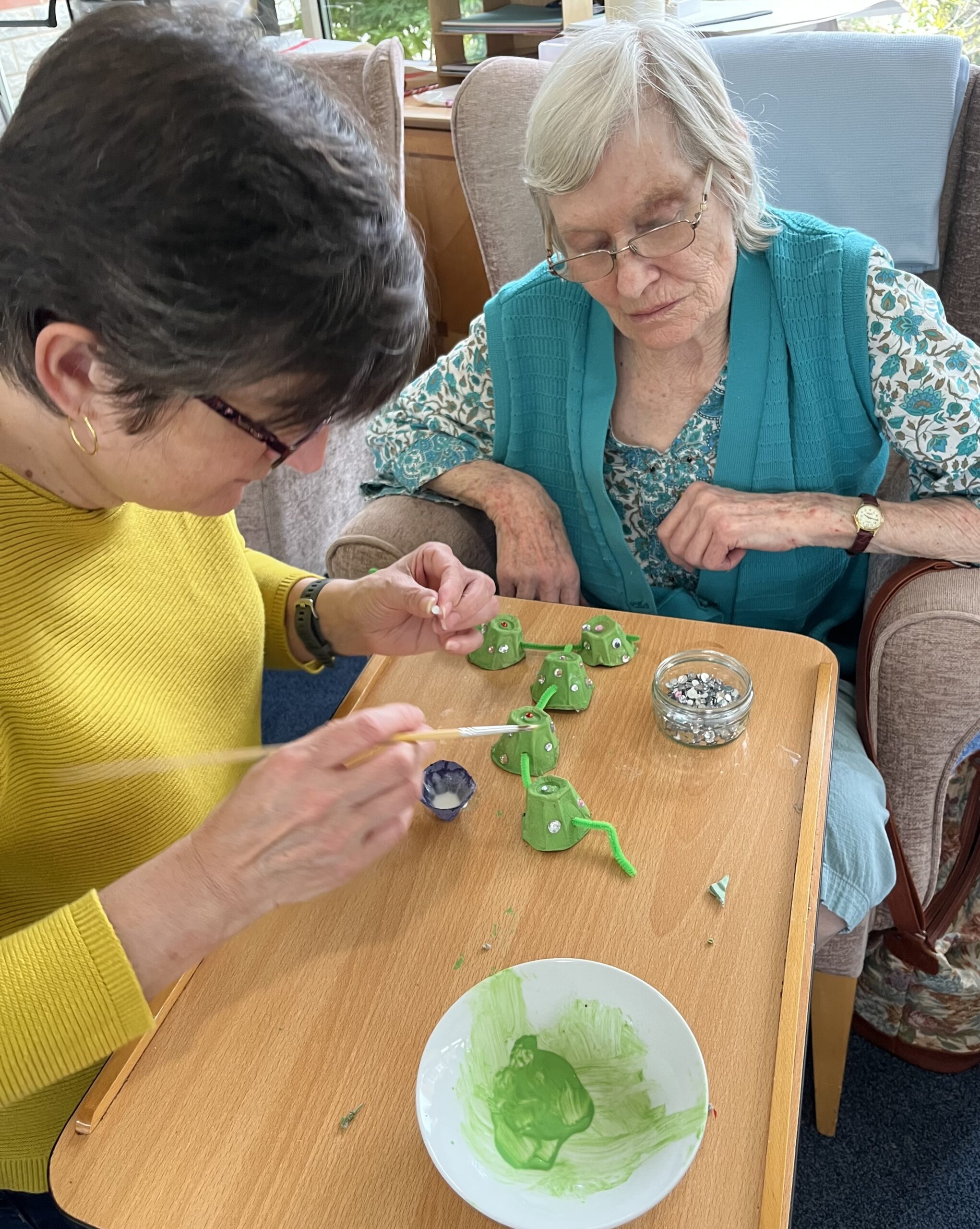 Wendy and helper gluing sequins to her dragon