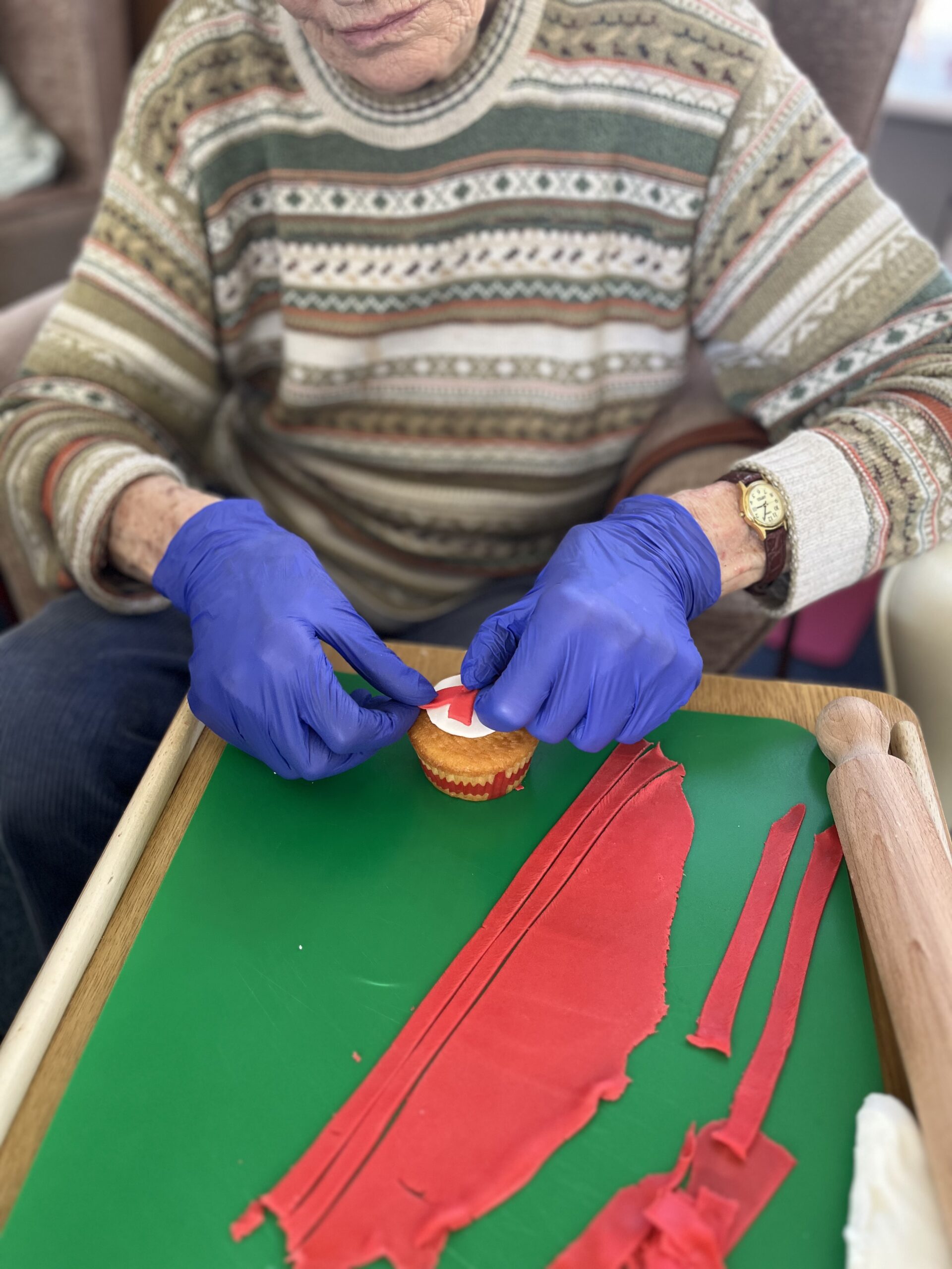 Wendy placing red cross icing onto cupcakes scaled