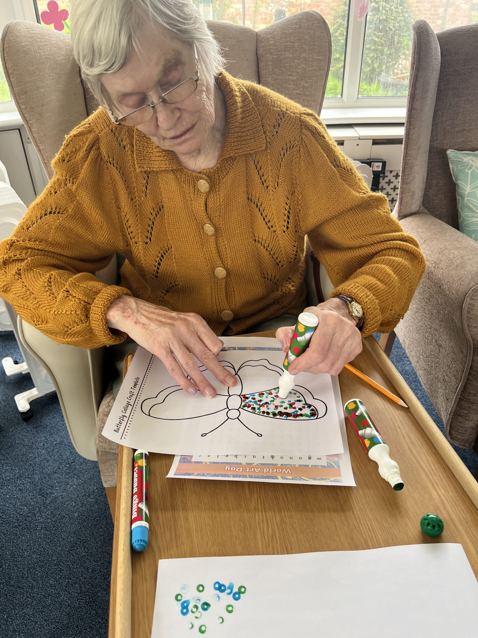 Wendy putting dots on colour on her butterfly with felt-tip pen