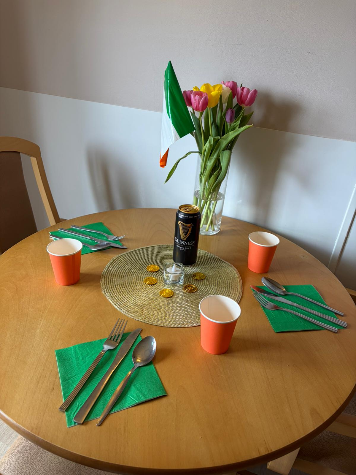 A table decorated with green napkins, orange cups and a can of Guinness