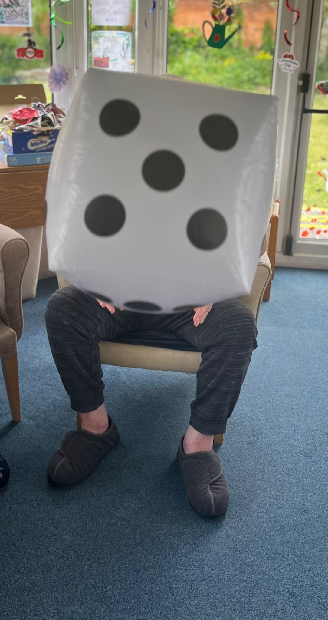 Bill seated holding a large blow-up dice