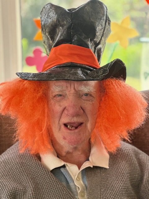 Bill wearing a bright orange wig with a black top hat like the Mad Hatter