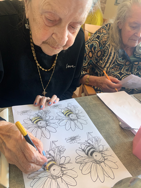 Female resident colouring in a bee with a yellow felt-tip pen