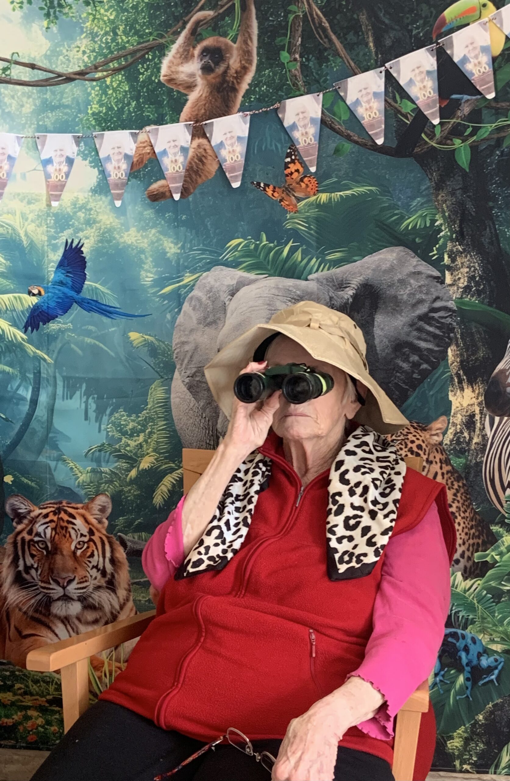 Female resident looking through binoculars seated in front of jungle back drop